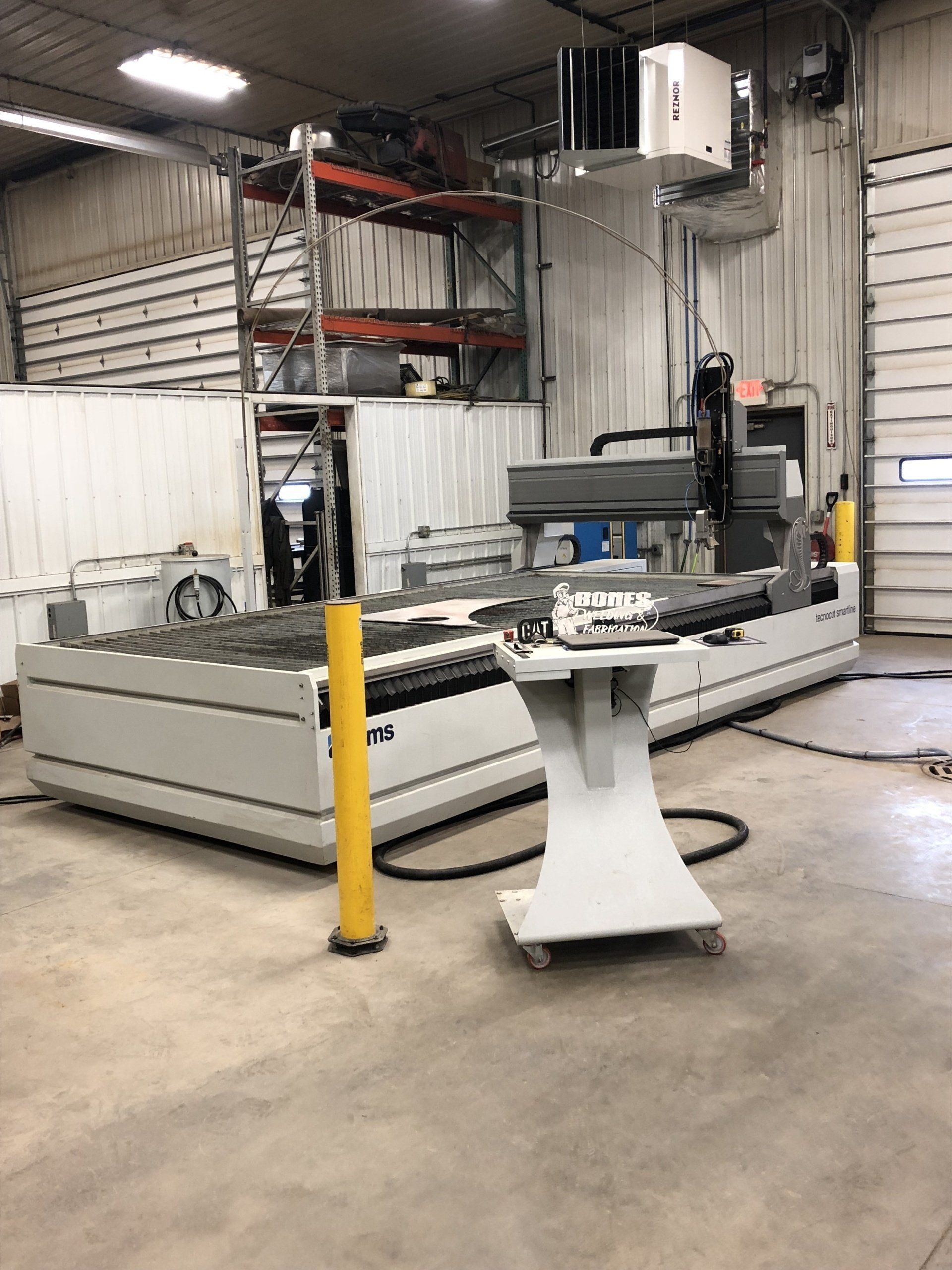 A machine is sitting in a garage next to a yellow pole.