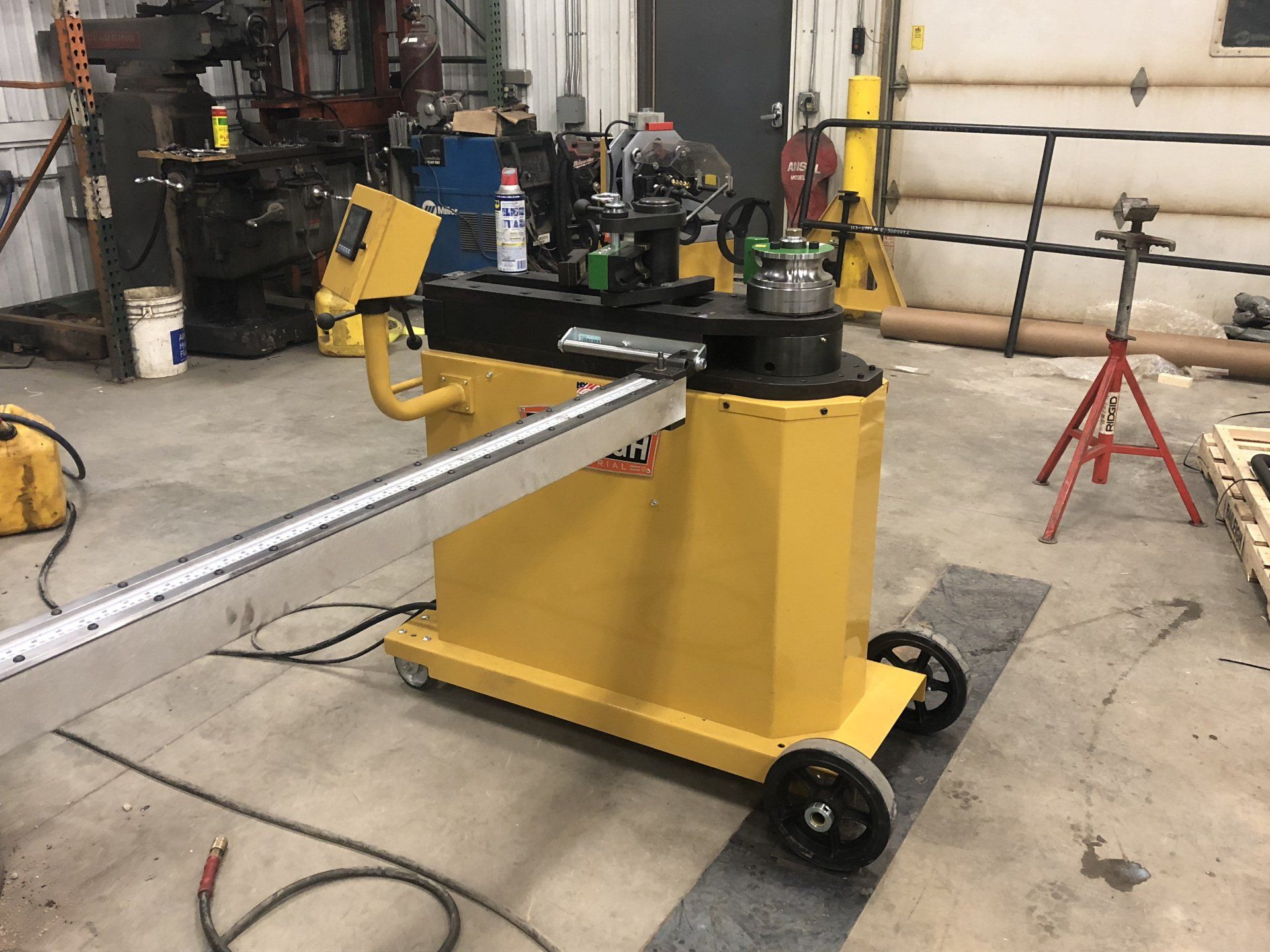 A yellow pipe bending machine is sitting in a garage.