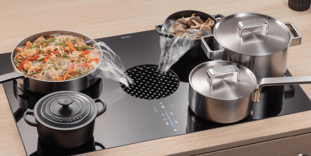 A cooktop with multiple pots and pans steaming, with a central vent to remove the steam.