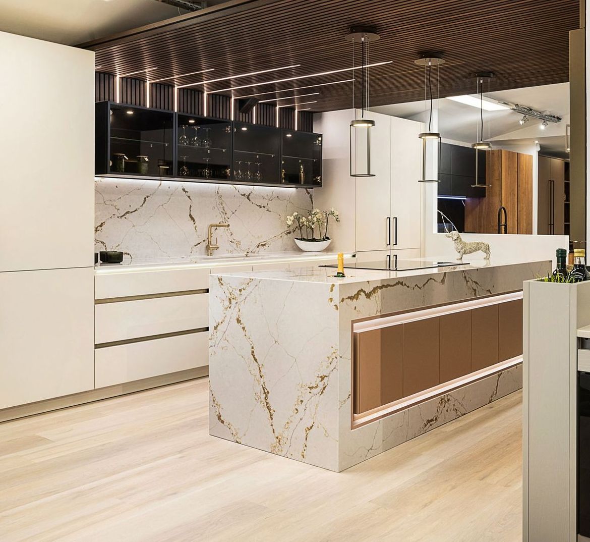 Modern kitchen with marble countertops, wood accents, and light fixtures.