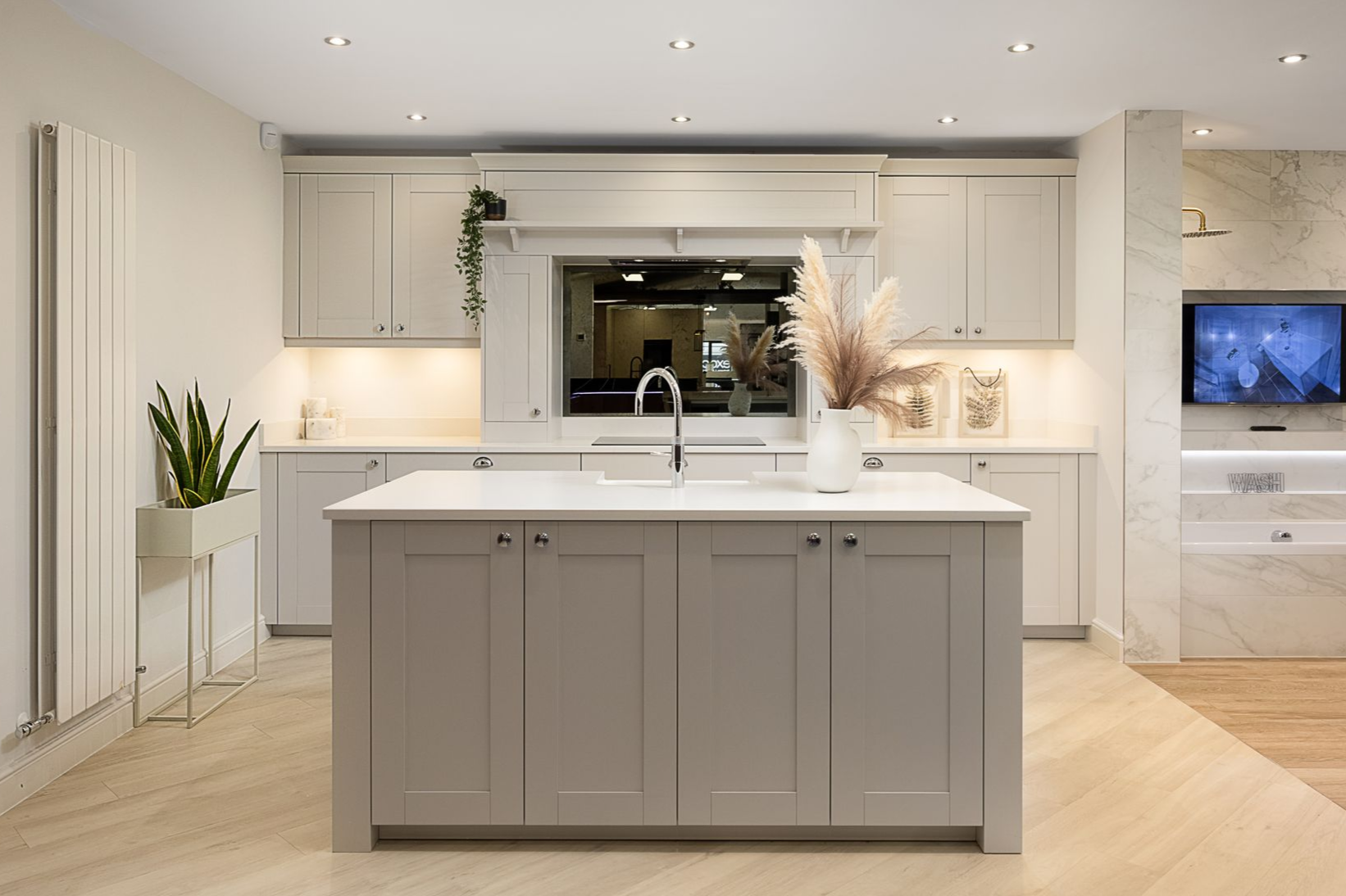 Modern kitchen with gray island, light cabinets, and large window.
