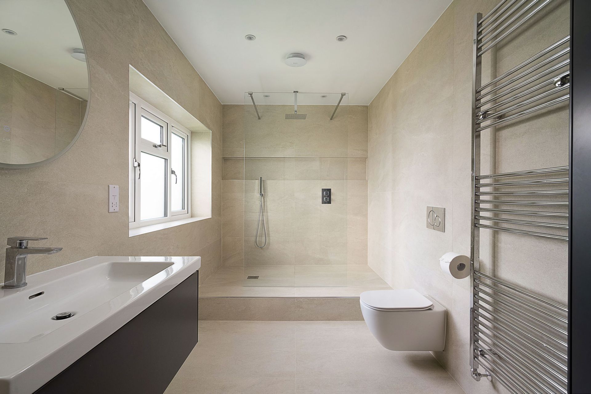 Modern bathroom with shower, toilet, sink, and heated towel rack. Neutral colors, natural light.