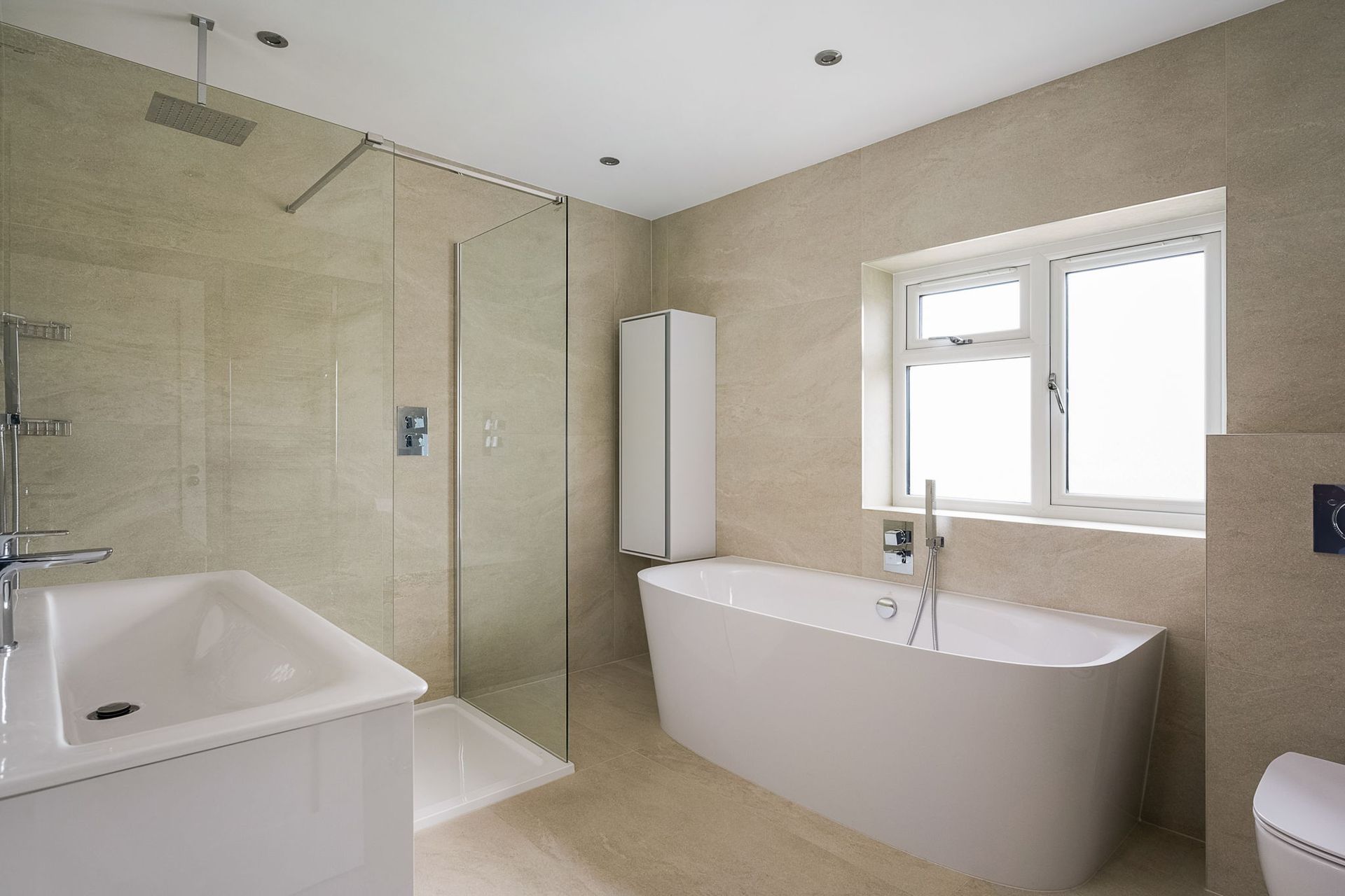 Modern bathroom with a white tub, shower, sink, and neutral-colored tiled walls.