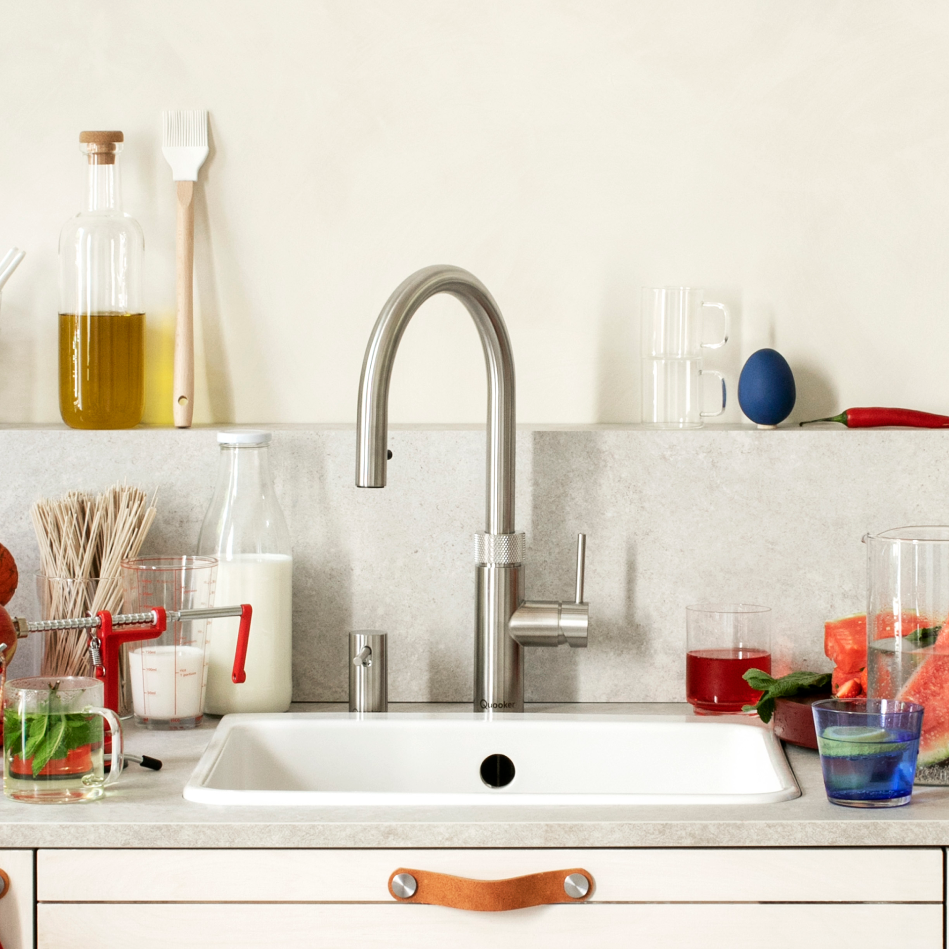 Kitchen sink with faucet, surrounded by food, drinks, and utensils.