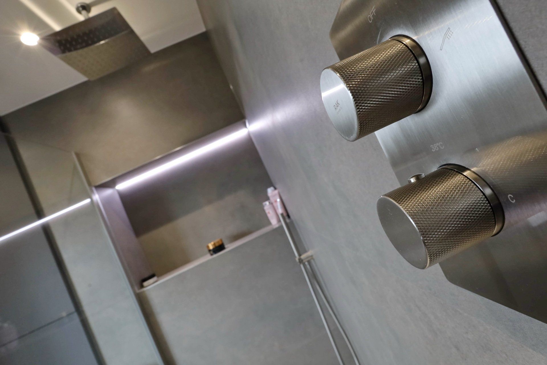 Modern gray shower with built-in controls and a showerhead; sleek design, minimalist.