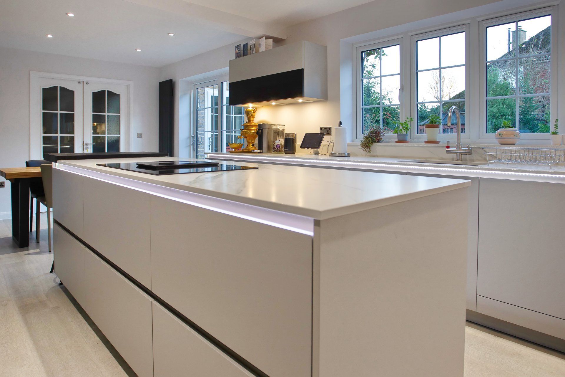 Modern kitchen with large island and built-in stovetop; cabinets are light gray.