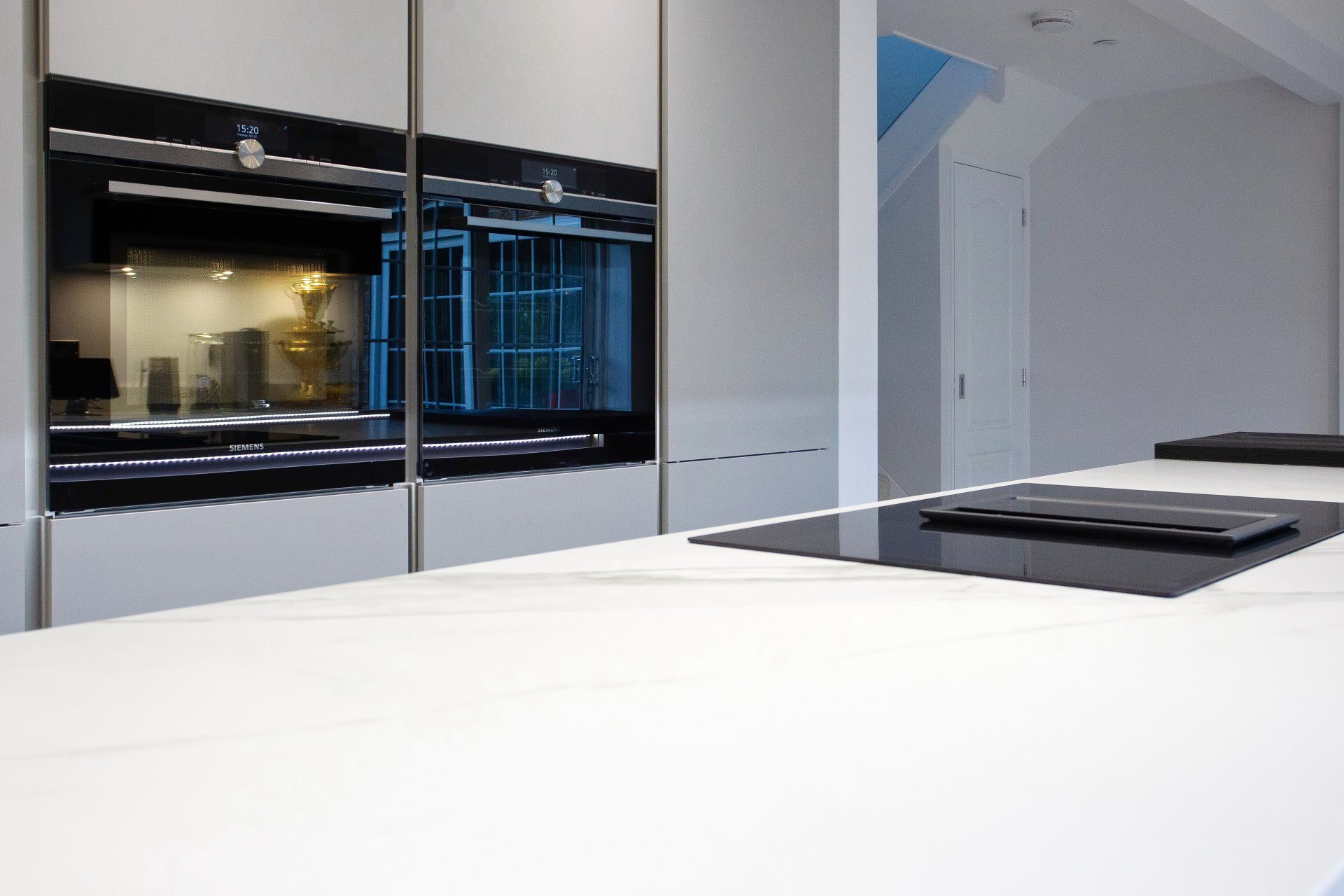 Modern kitchen with white countertops and built-in black oven.