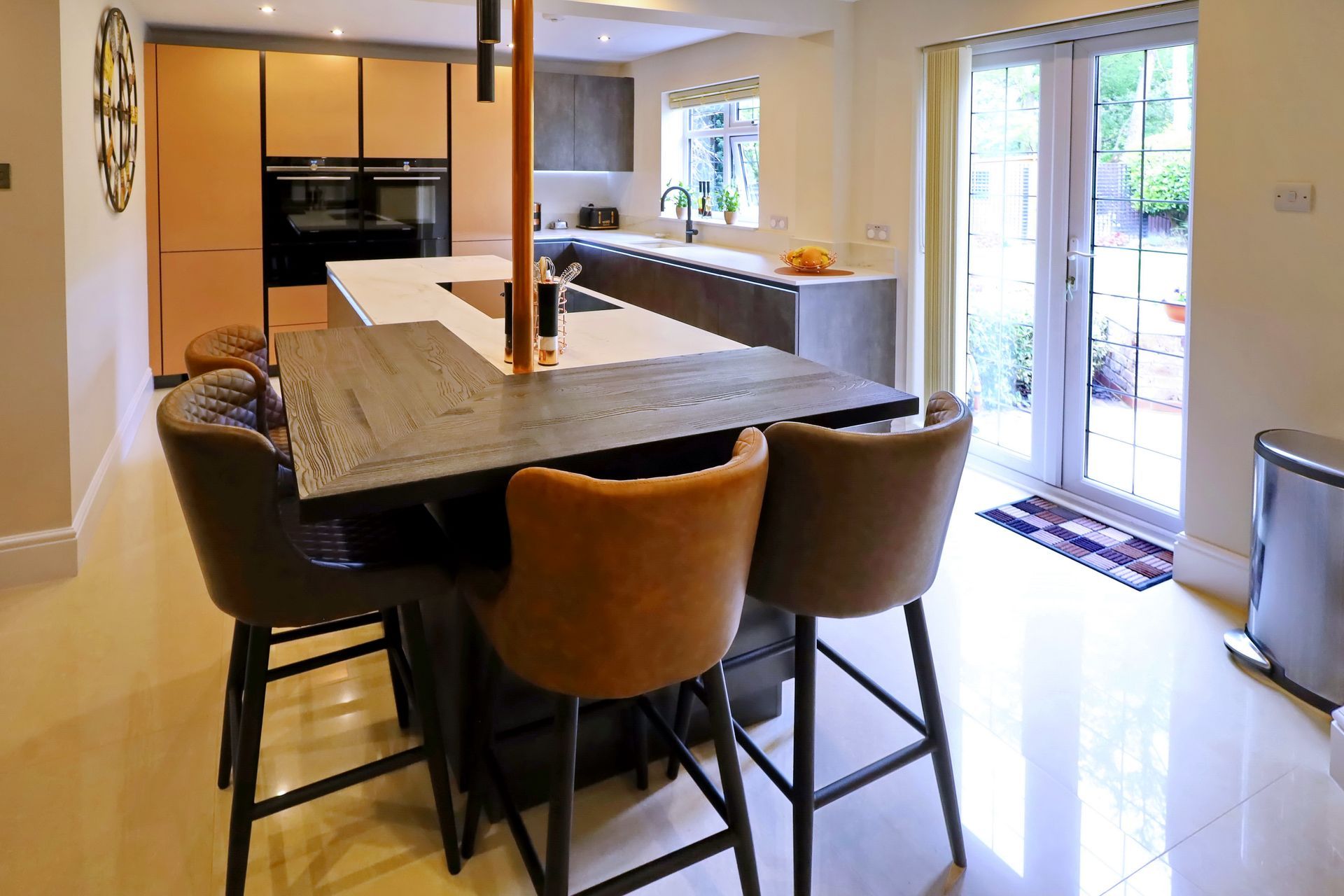 Modern kitchen with island and bar seating, light wood cabinetry, white countertops, and French doors.