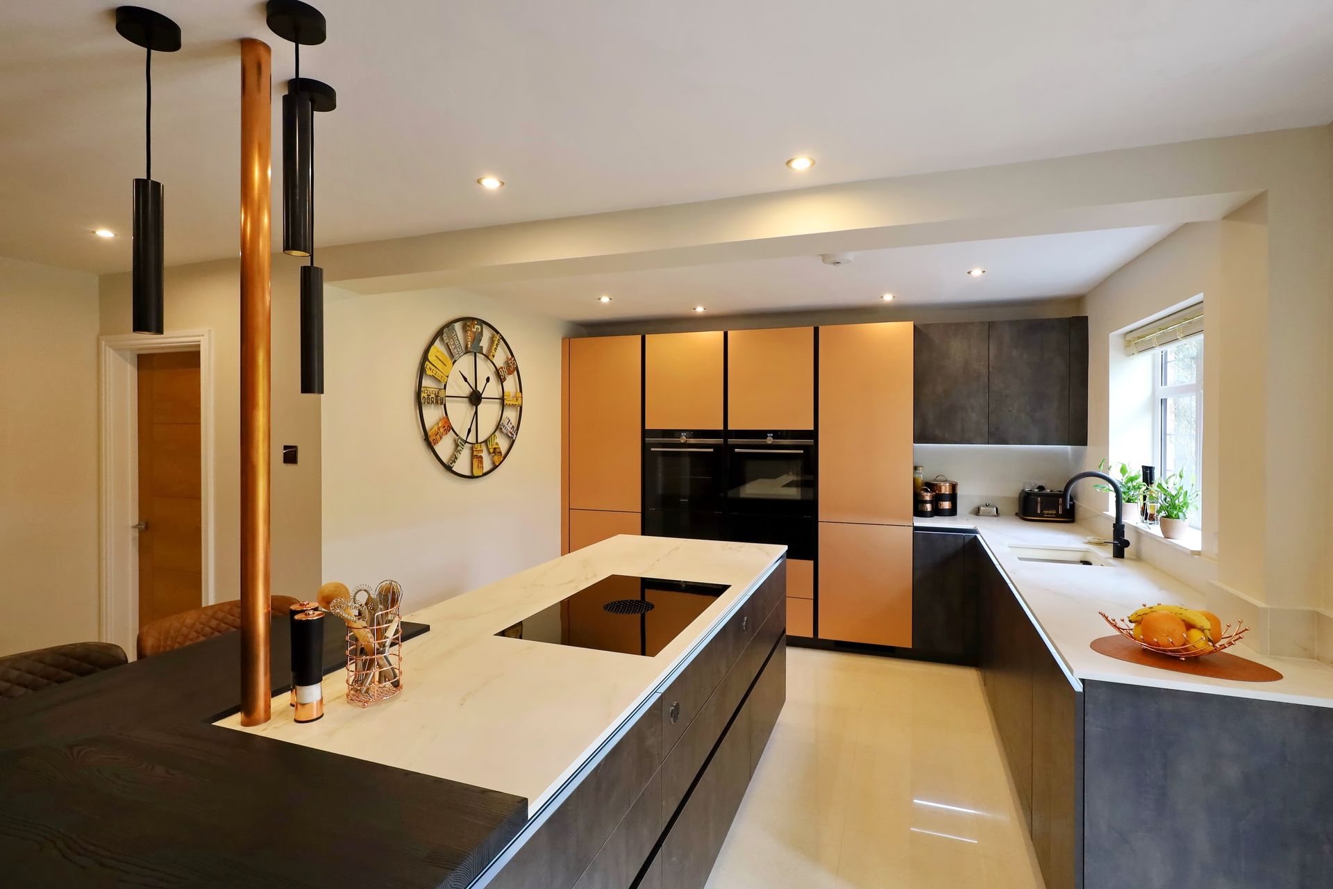 Modern kitchen with island, copper accents, and light-colored cabinets and countertops.