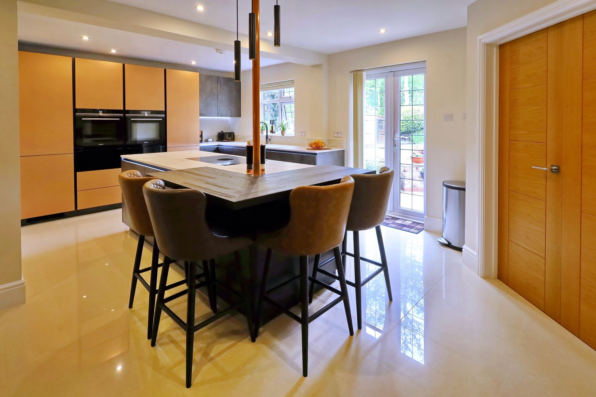 Modern kitchen with island, four bar stools, cabinets, and a door to the outside.