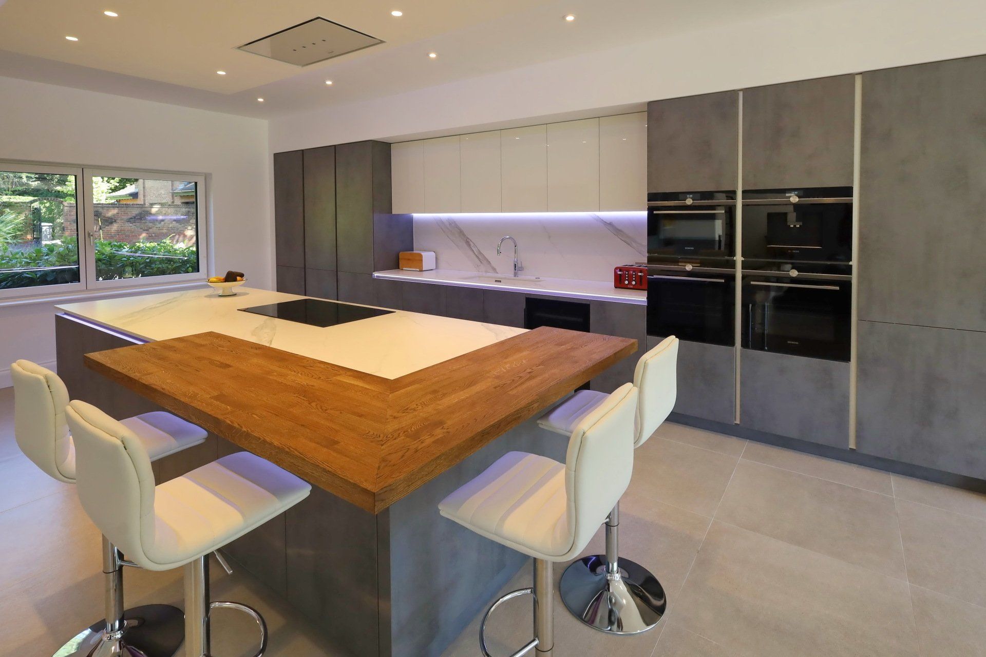 Harvey contemporary kitchen with grey, handleless units and teal furnishings. Designed by exact Kitchens in Wokingham.