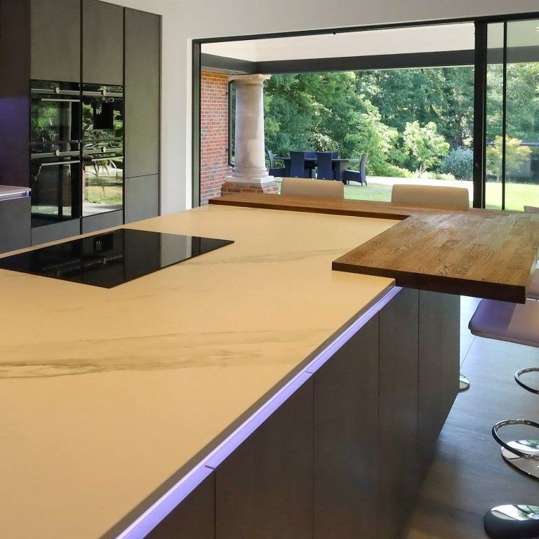 Modern kitchen island with stovetop, extending wooden countertop, overlooking outdoor patio.