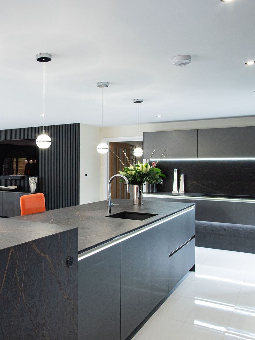 Modern gray kitchen with island, pendant lights, and stainless steel faucet.