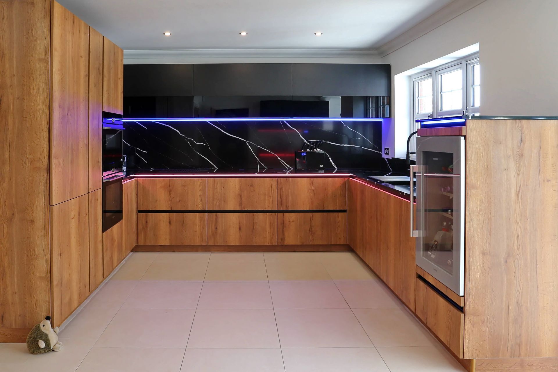 Modern U-shaped kitchen with wood cabinets, black countertop, white floor, and a wine cooler.