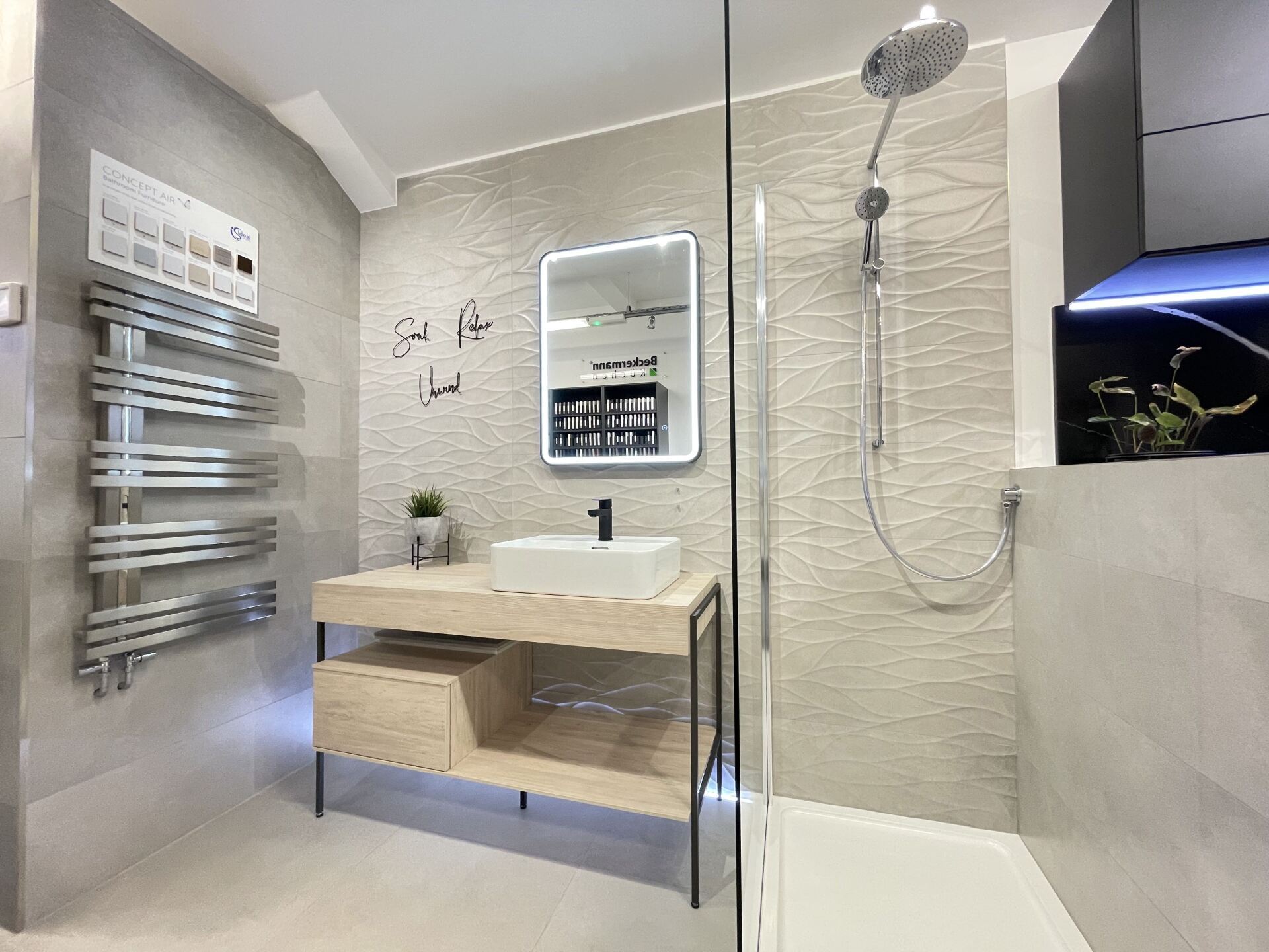 Modern bathroom with a shower, vanity, and towel warmer. Neutral tones, light wood and gray tile.
