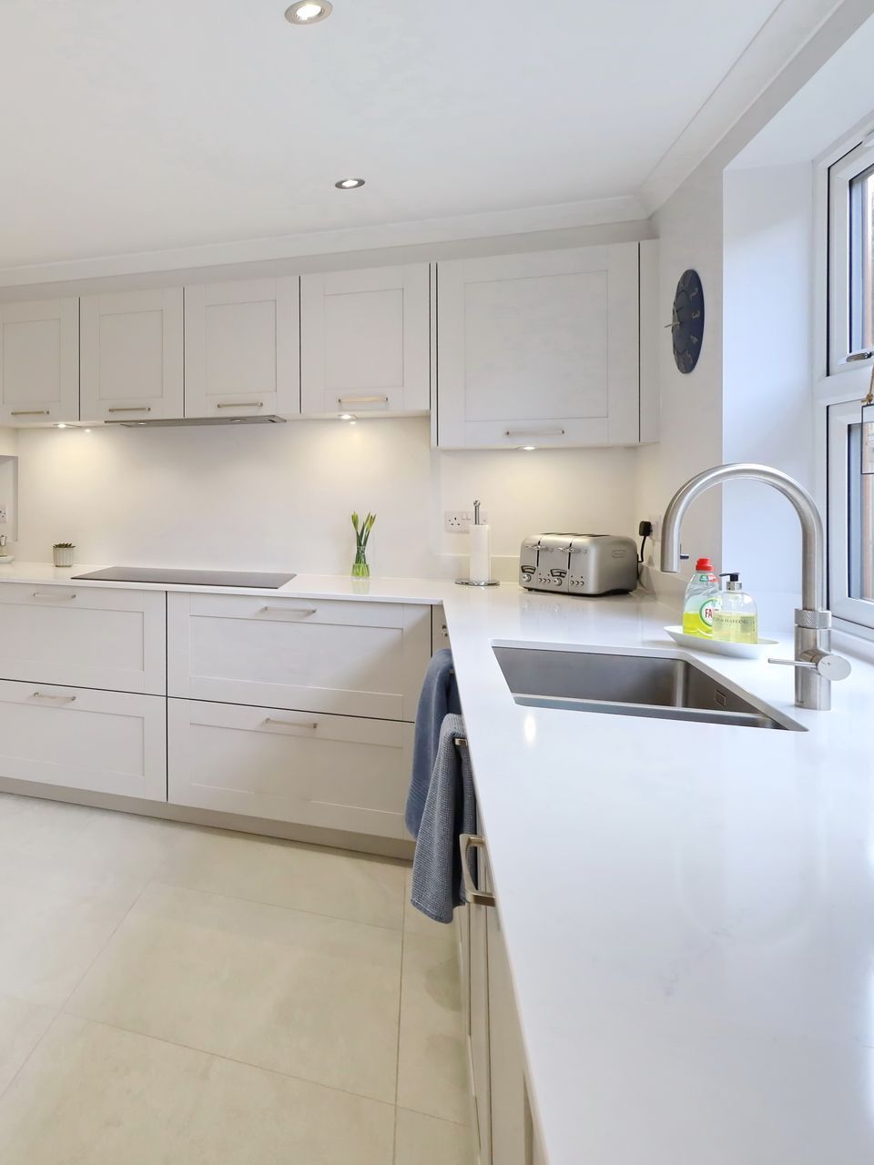 White kitchen with cabinets, countertops, and stainless steel sink.
