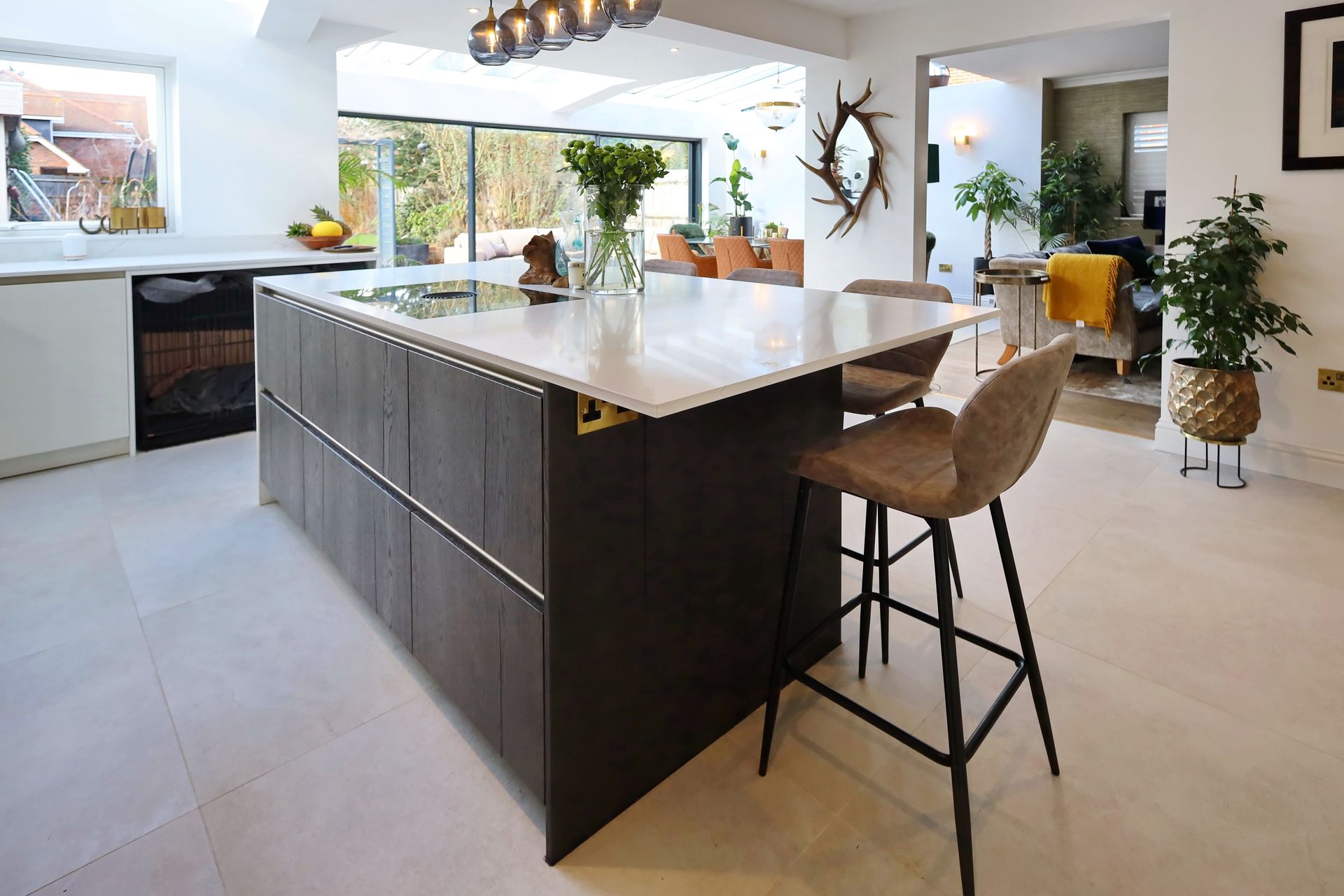 Modern kitchen with island, marble countertop, bar stools, and dark cabinets.
