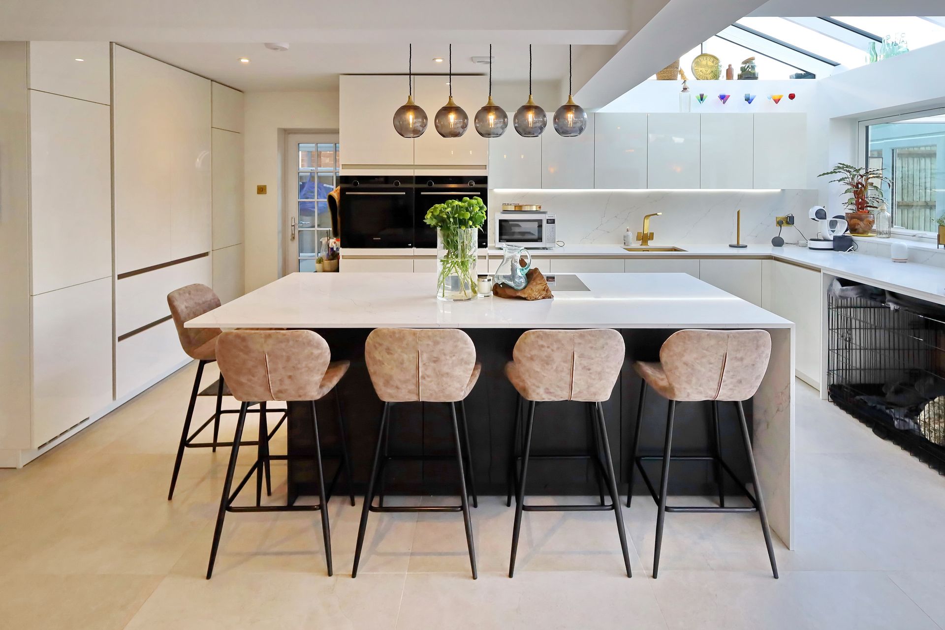 Modern kitchen with an island and bar stools, featuring neutral cabinets and countertops with a skylight.