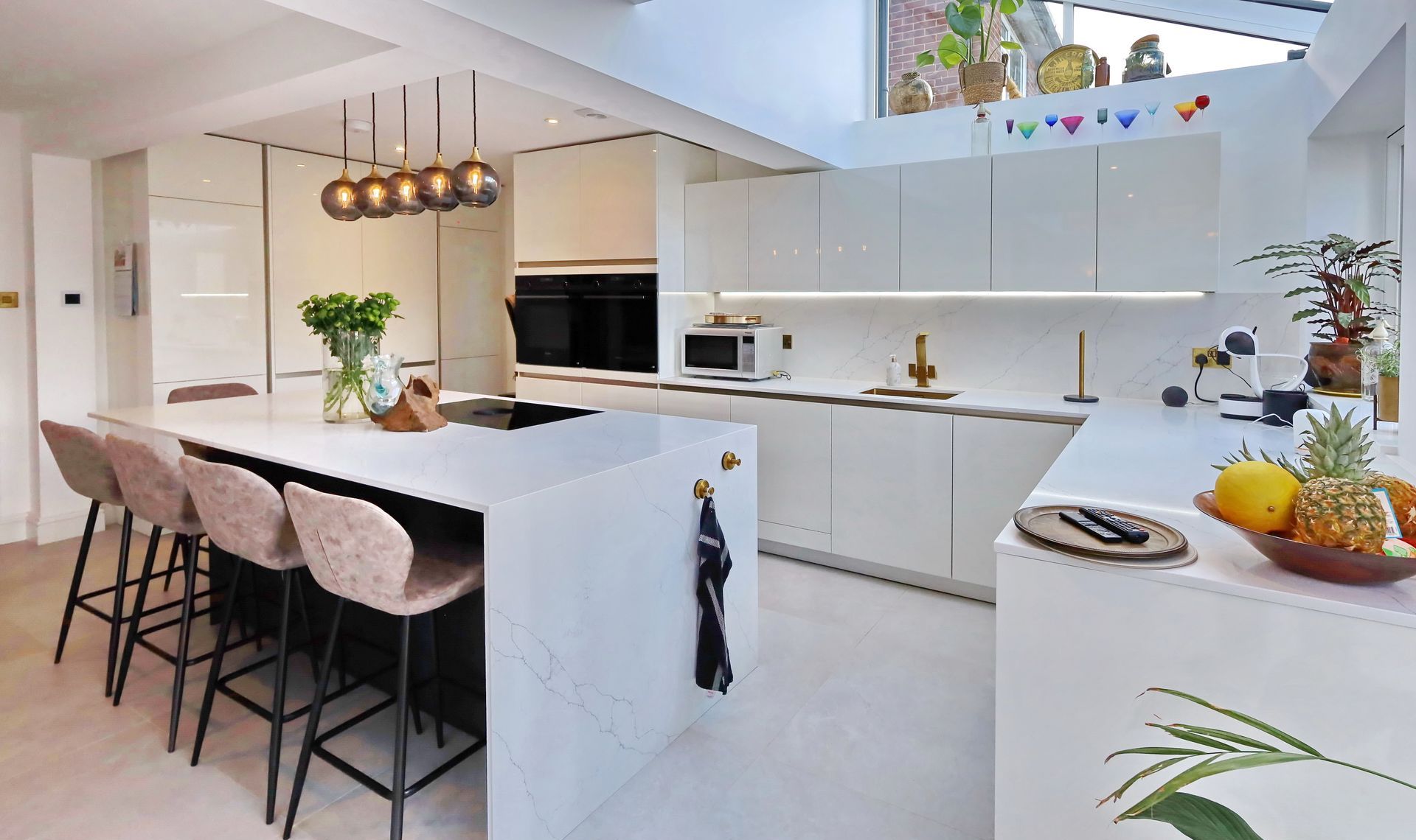 Modern white kitchen with island seating, black accents, and pendant lights.
