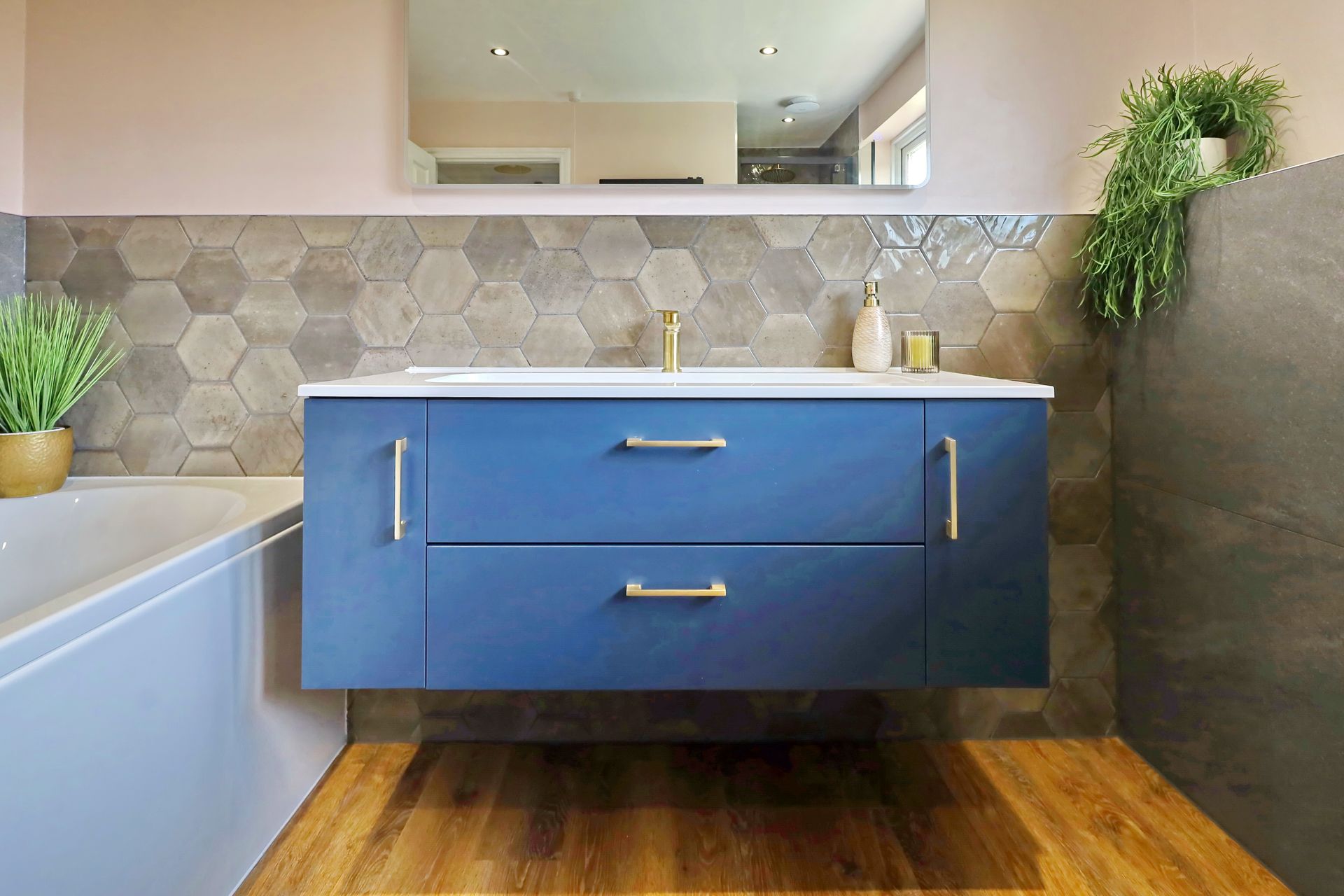 A bathroom with a blue vanity, sink, mirror and bathtub, designed by exact Kitchens & Bathrooms, Wokingham.