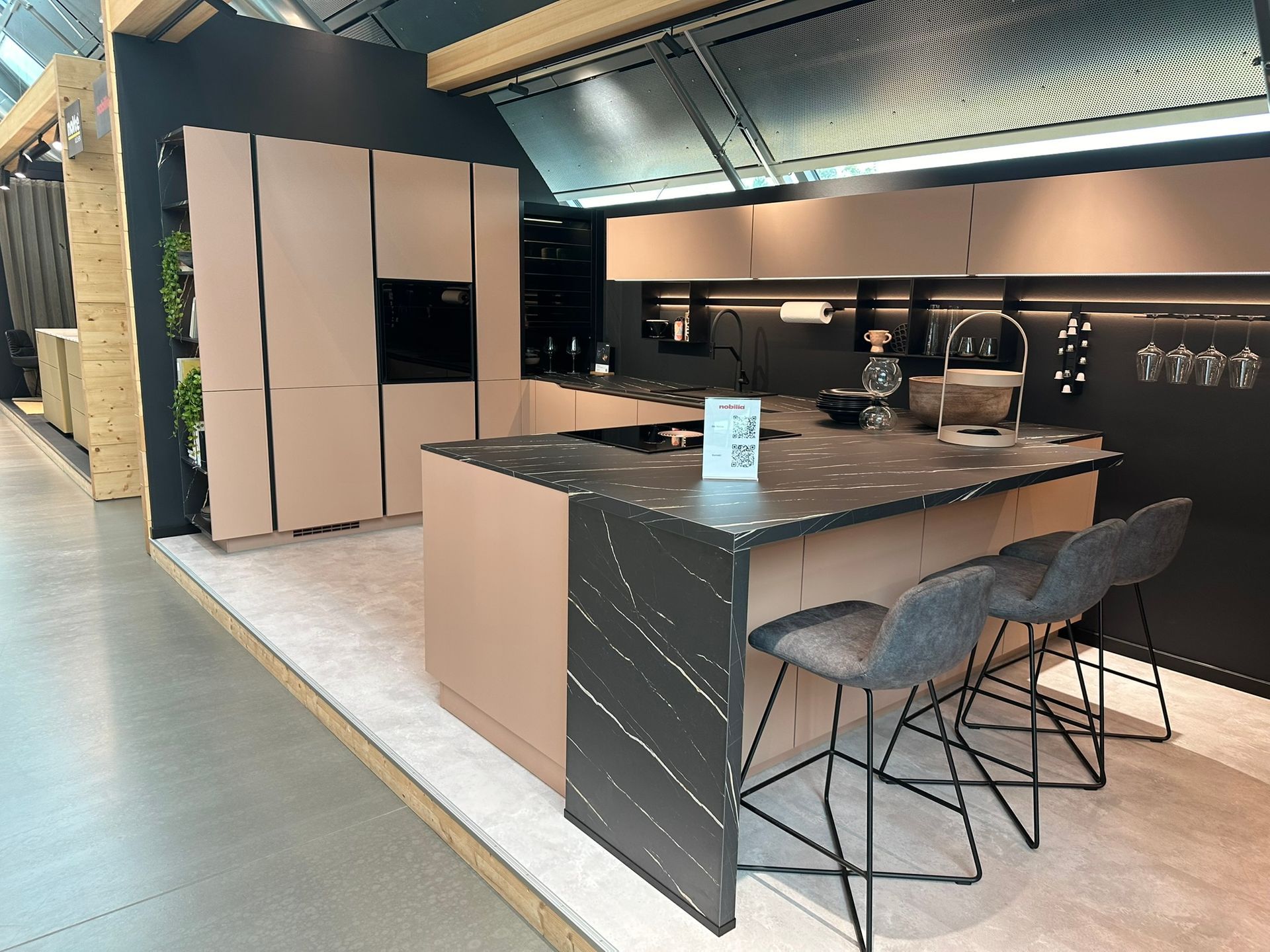 Modern kitchen with beige cabinets, black island, and three gray bar stools.