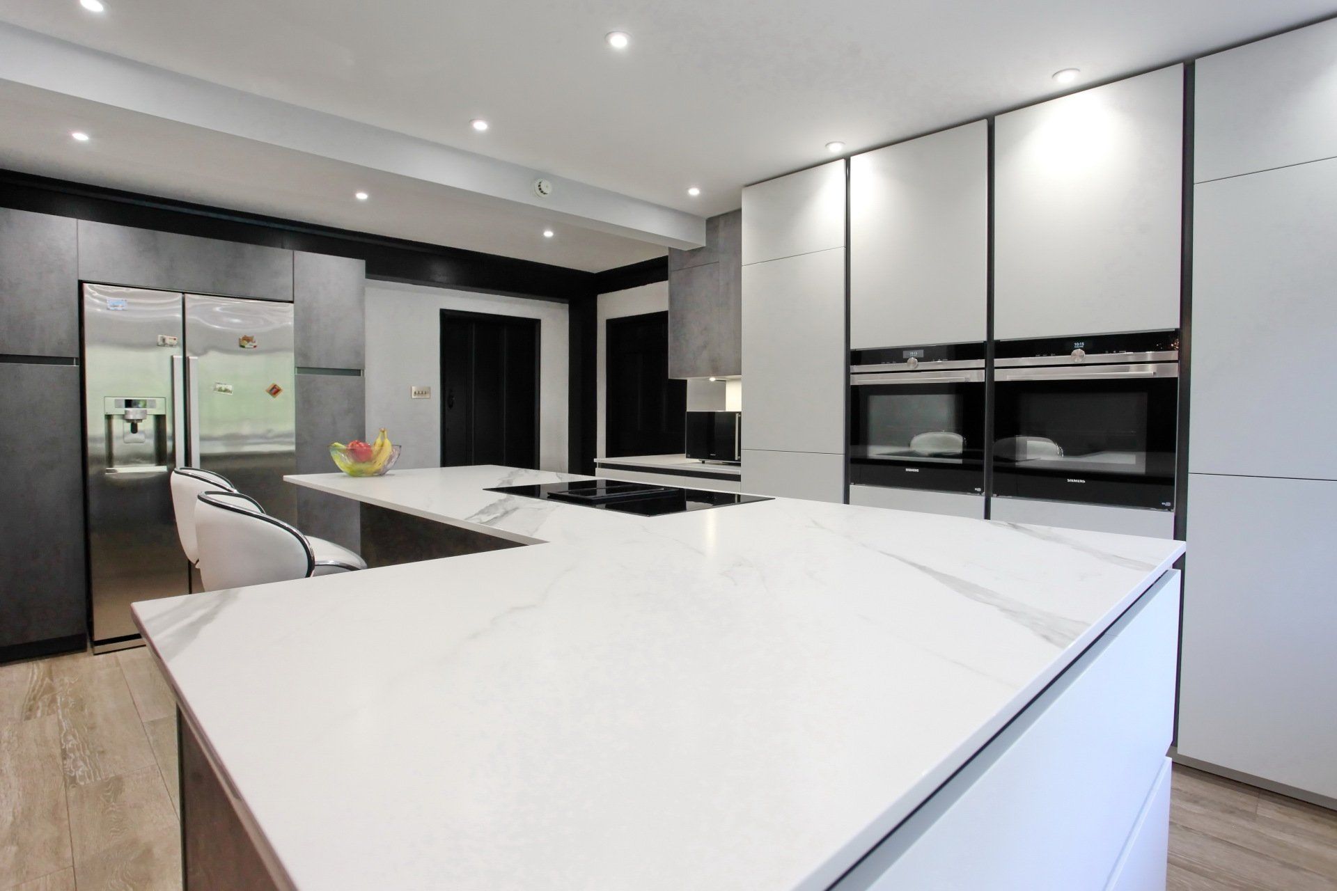 Modern kitchen with white countertops and cabinets, a large island, and built-in appliances.