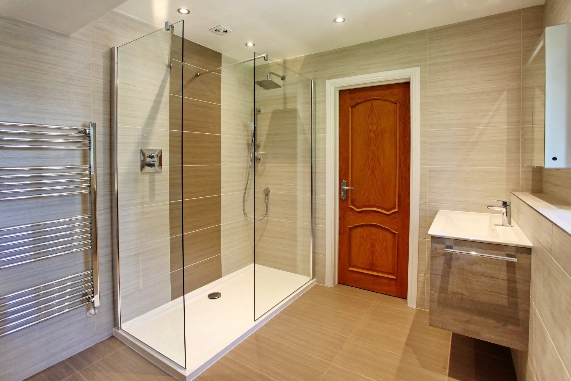 Modern bathroom with a glass shower, wooden door, and floating vanity.