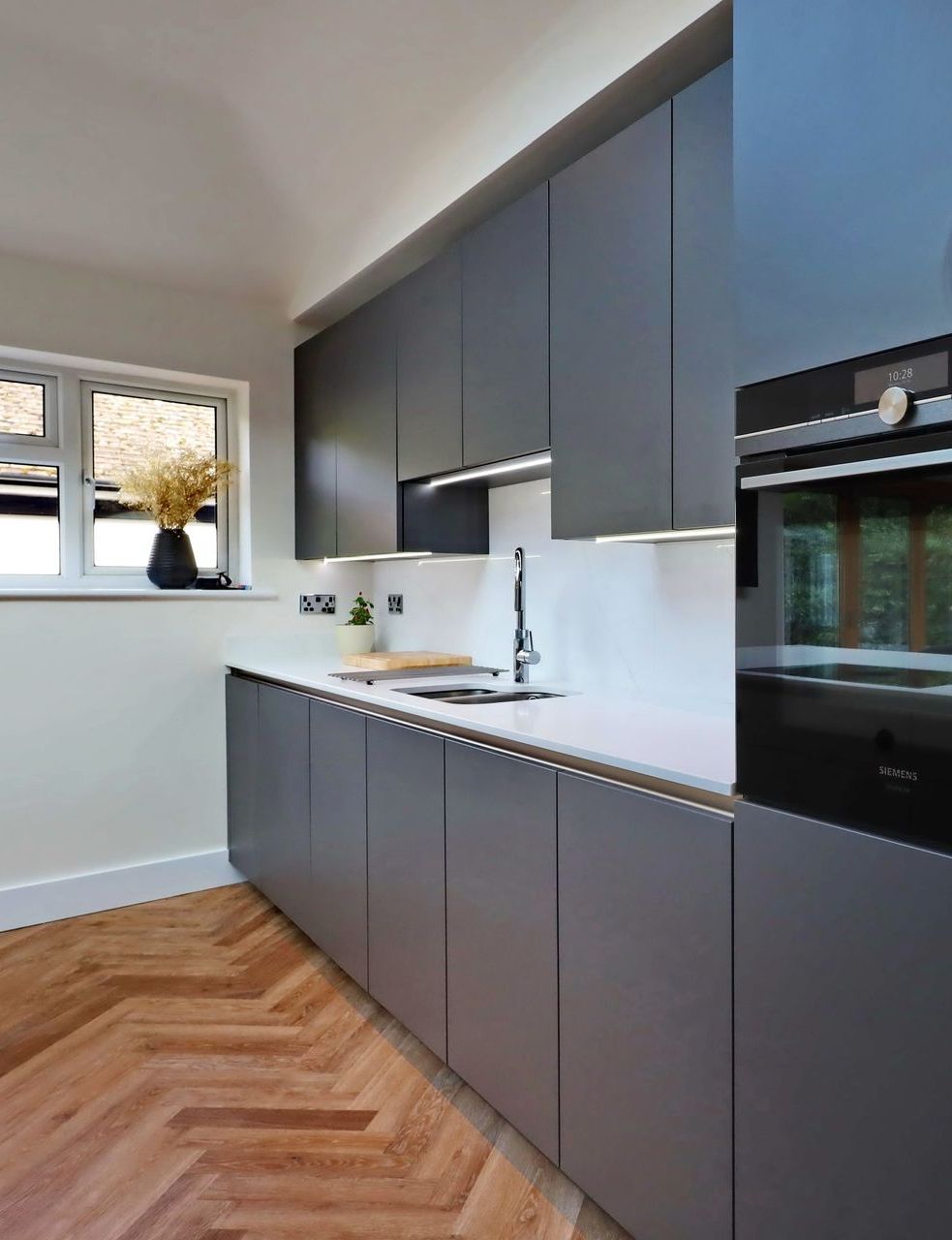 Harvey contemporary kitchen with grey, handleless units and teal furnishings. Designed by exact Kitchens in Wokingham.