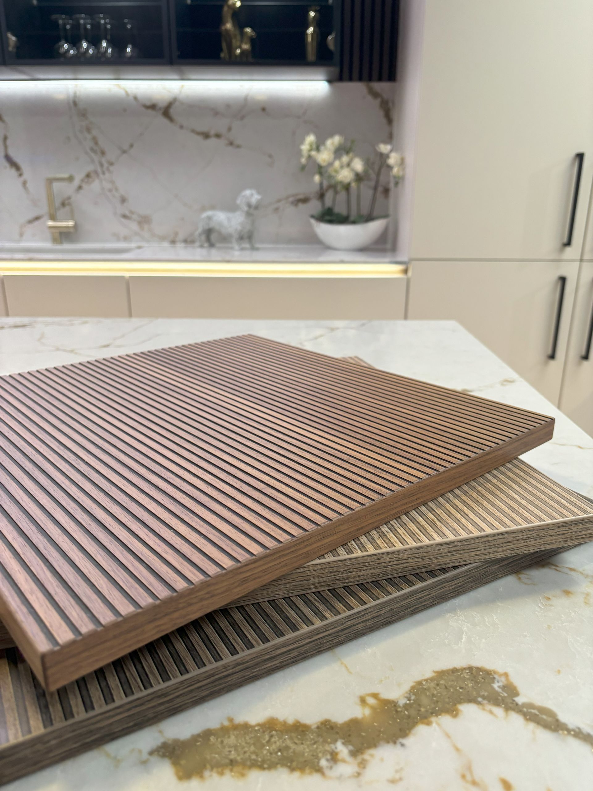 Three wooden acoustic panels on a marble countertop with kitchen cabinetry in background.