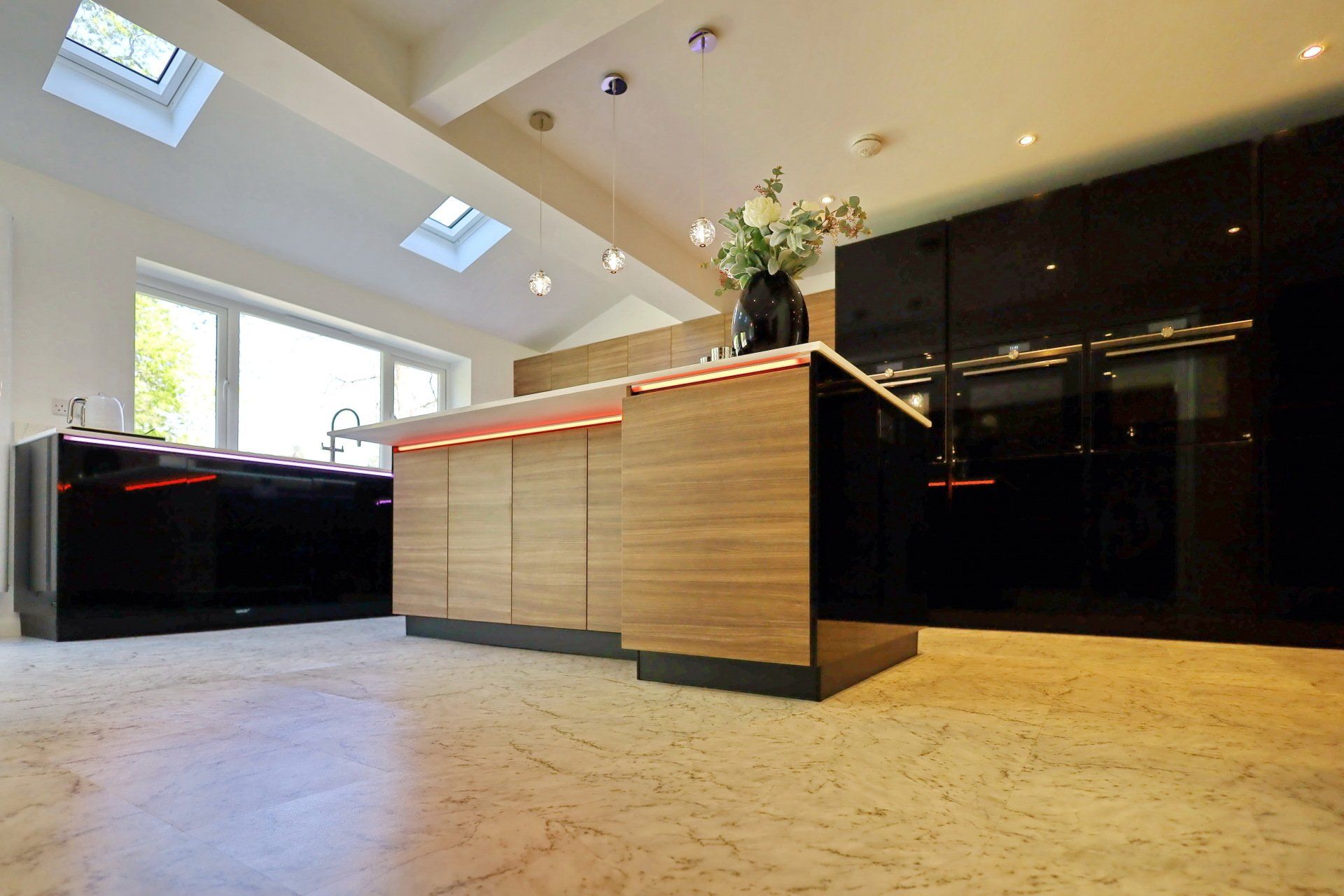 Modern kitchen with black cabinetry, wooden island, and skylights.