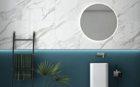 Bathroom with marble tile wall, teal lower wall, round lit mirror, and a towel ladder.