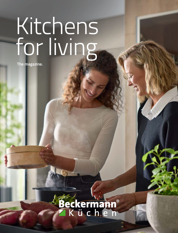 Two women in a modern kitchen. One holds a steamer basket; the other smiles.