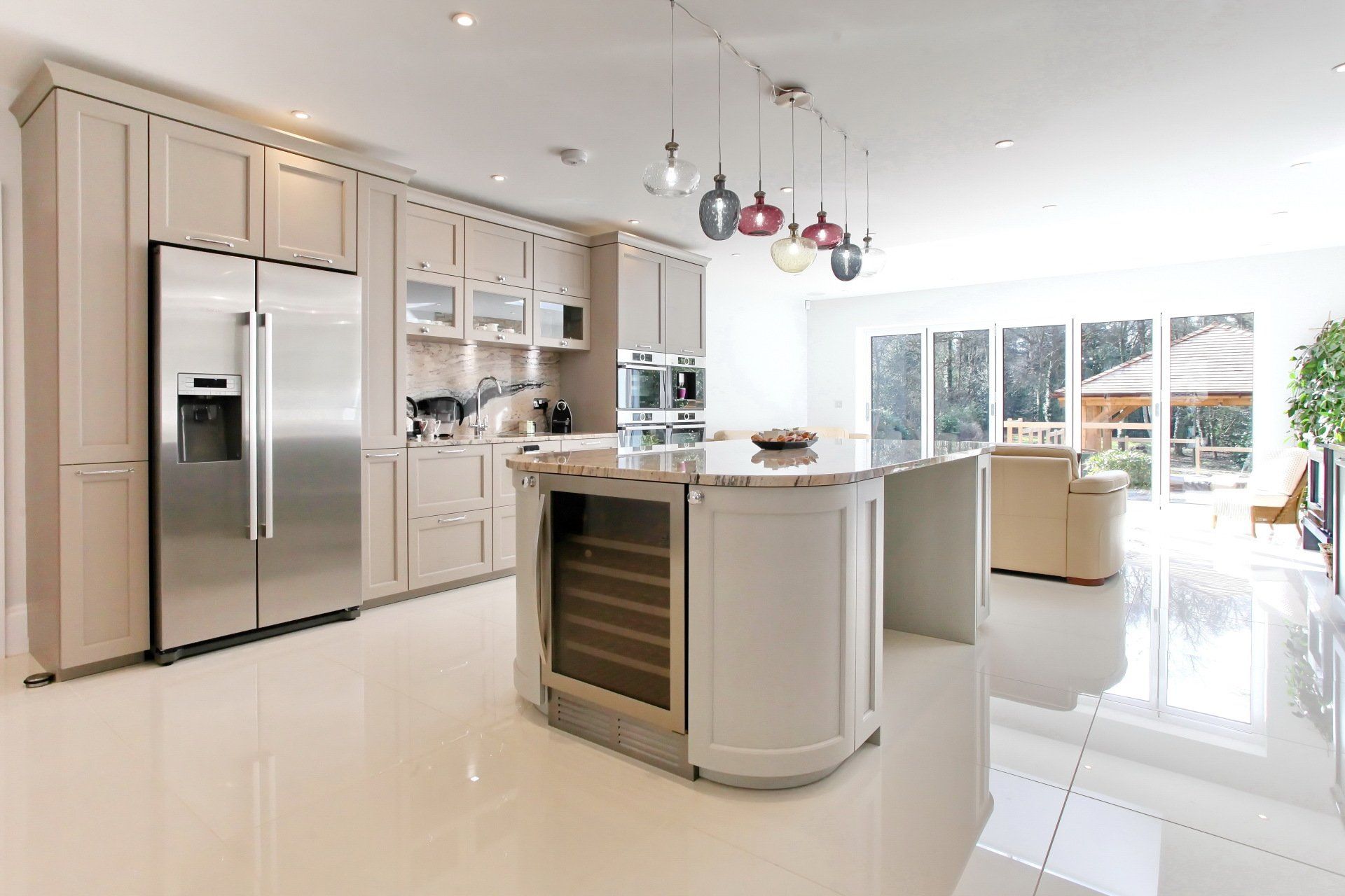 Modern kitchen with stainless steel appliances, light cabinets, and a central island with a wine fridge.