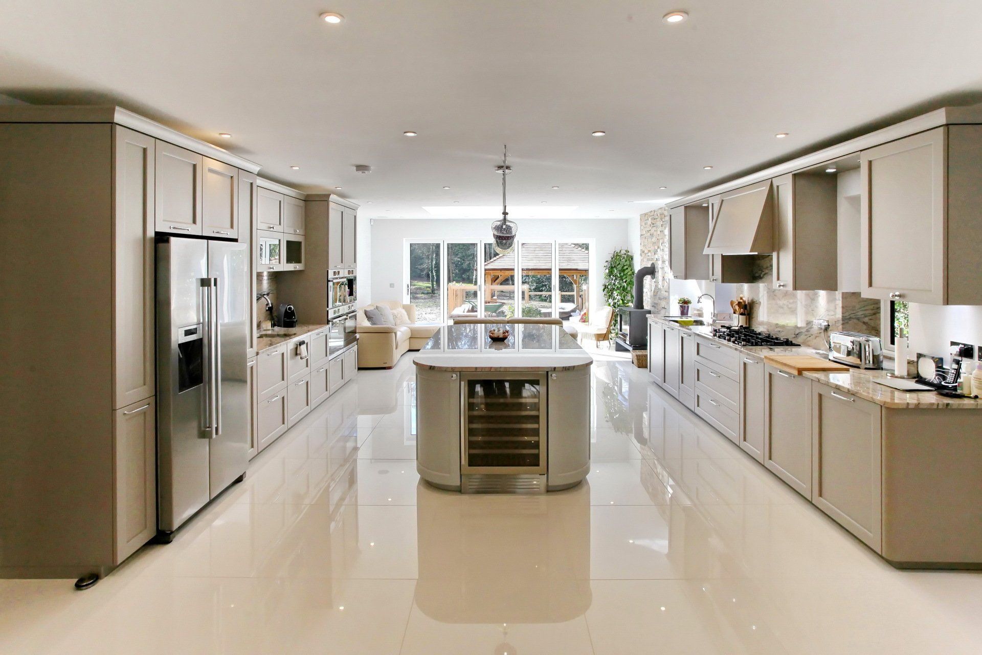 Spacious modern kitchen with island, stainless steel appliances, and large windows overlooking a patio.