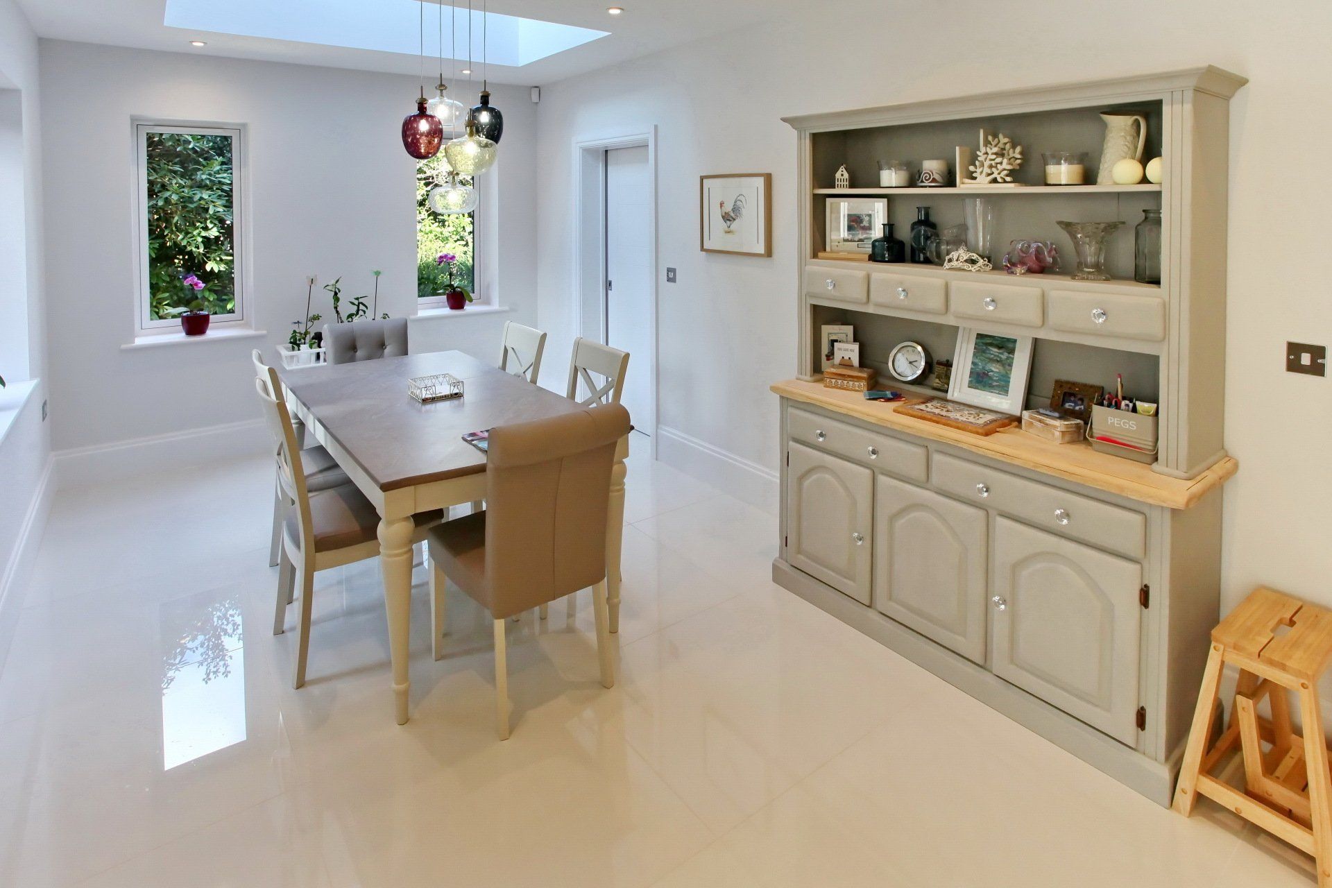 Dining room with a table, chairs, hutch, window and skylight. Beige and grey color scheme.