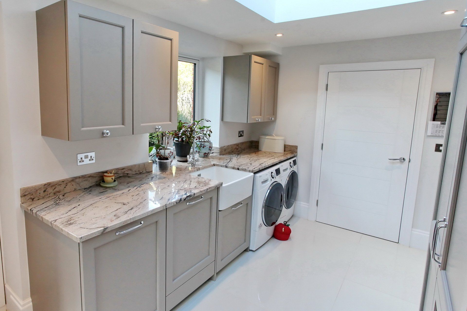 Laundry room with gray cabinets, granite countertops, white sink and appliances, and a white door.