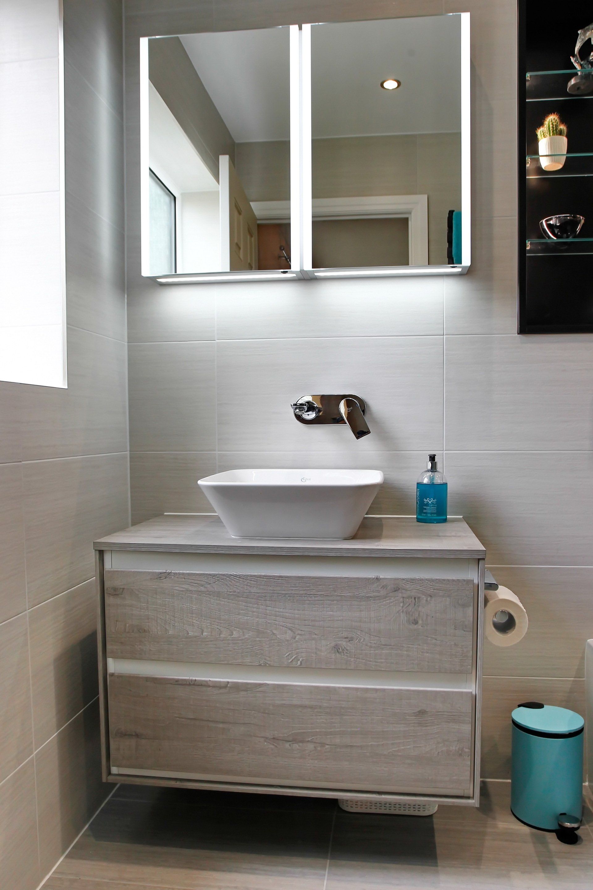 Modern bathroom with floating vanity, square sink, and mirrored medicine cabinet.