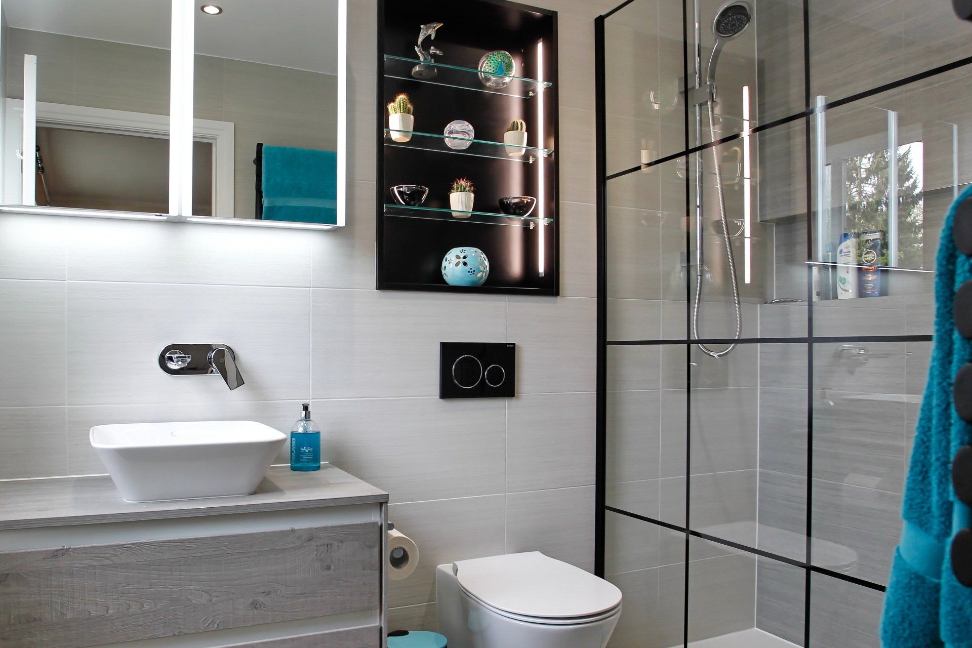 Modern bathroom with gray tiles, shower, vanity with sink, and a decorative wall display.