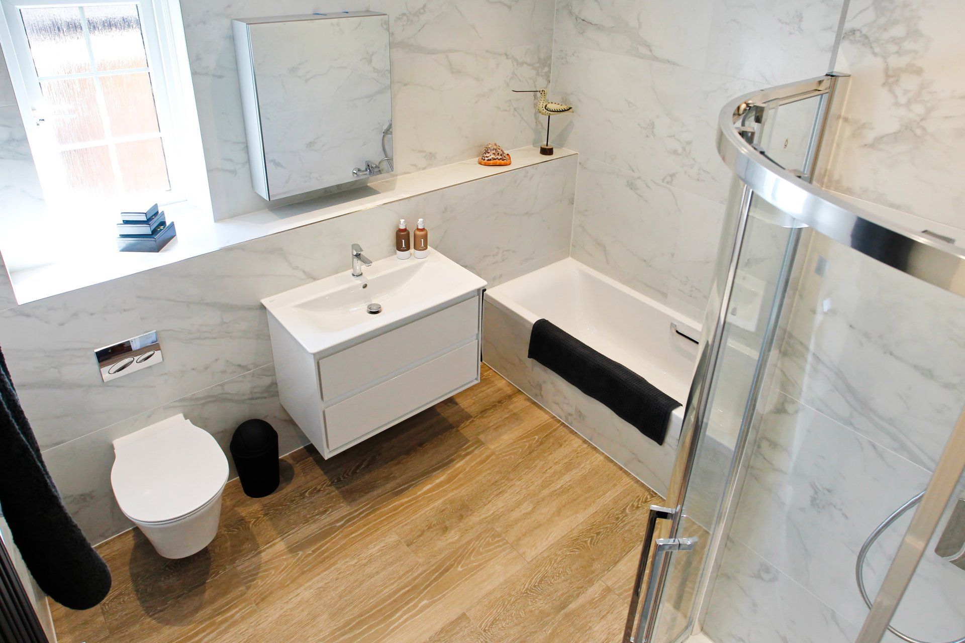 Modern bathroom with white and grey marble-look walls, a floating sink, and a shower stall.