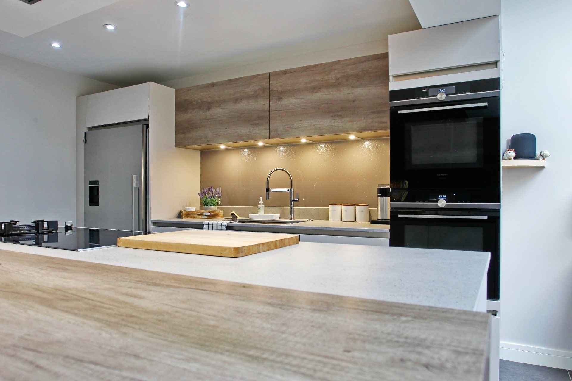Modern kitchen with light wood cabinetry, stainless steel appliances, and a light gray countertop.