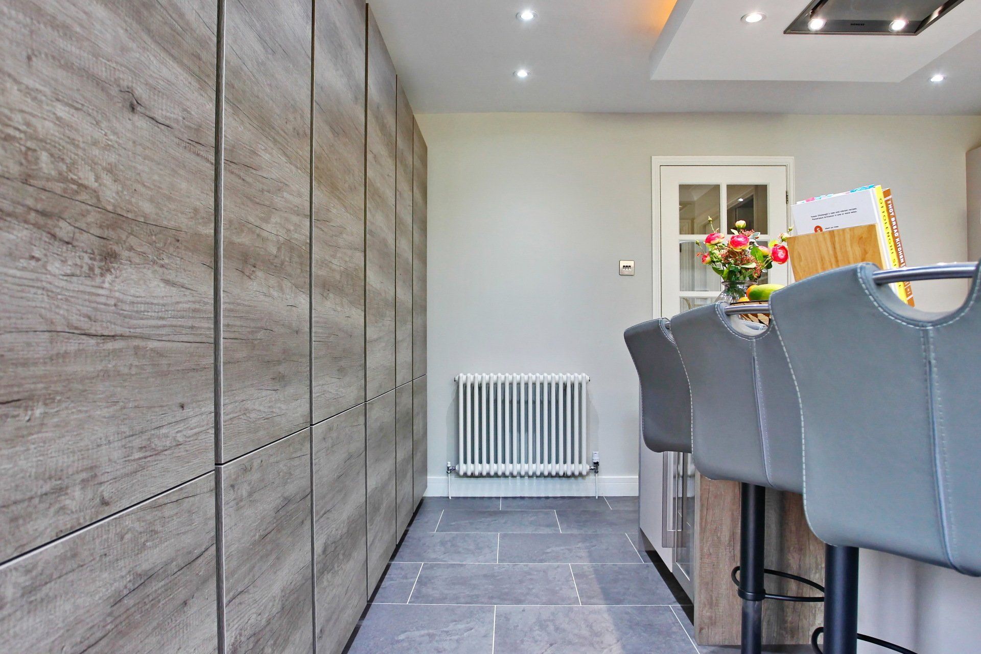 Kitchen interior with wooden cabinets, grey floor, and bar stools.