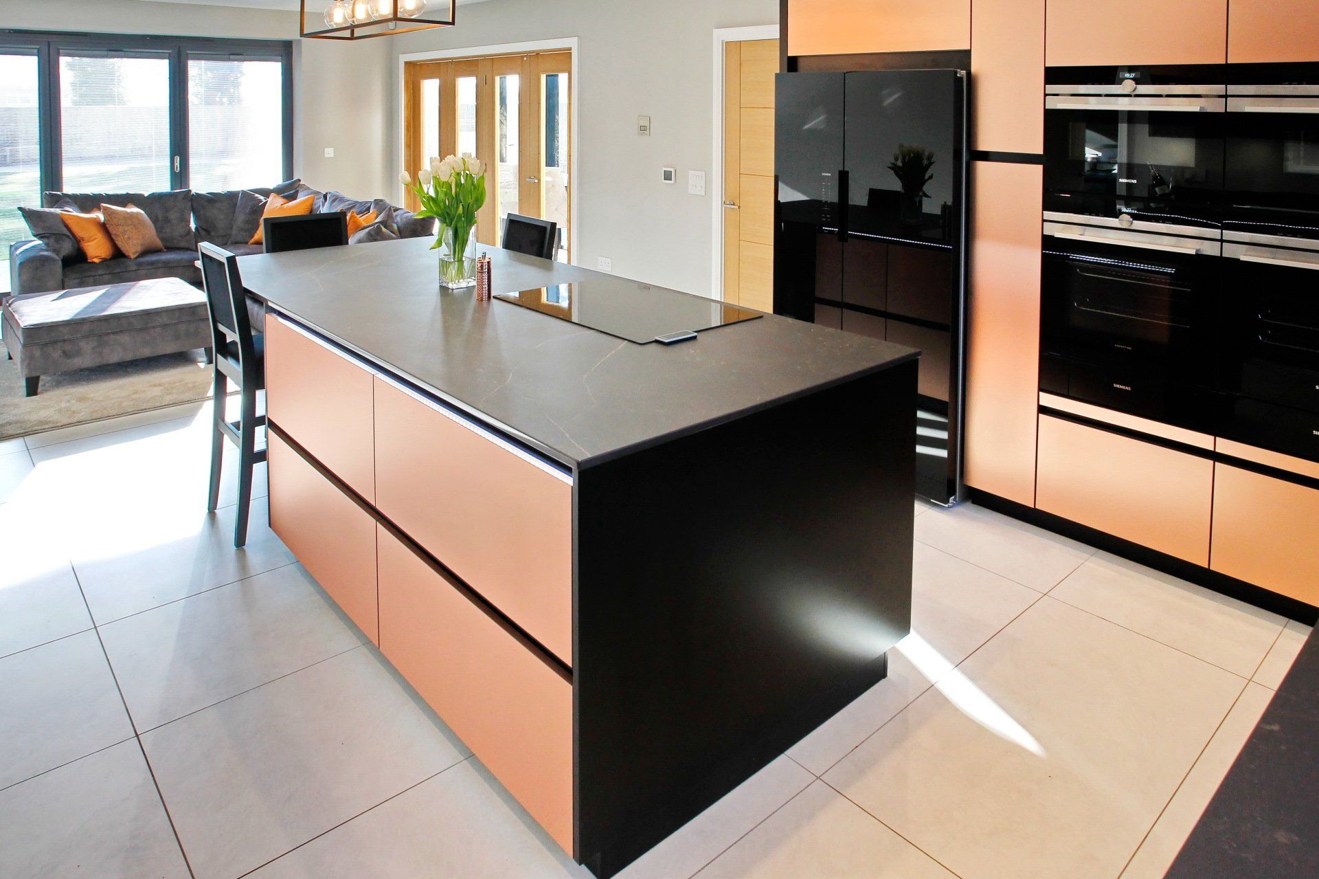 Modern kitchen with black island, copper cabinets, and stainless steel appliances.