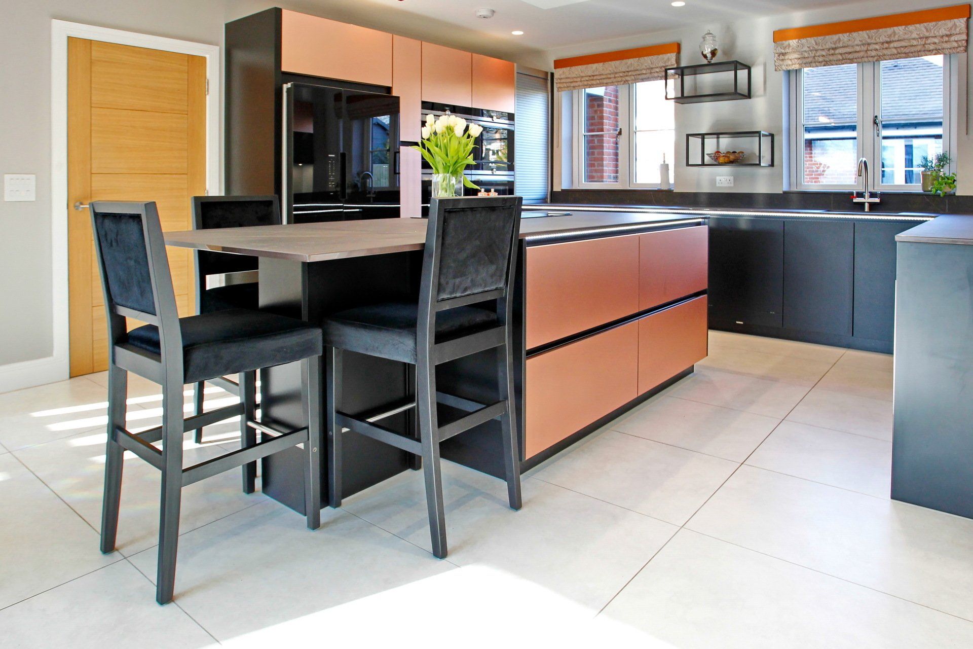 Modern kitchen with copper and black cabinetry, island with bar stools, and large windows.