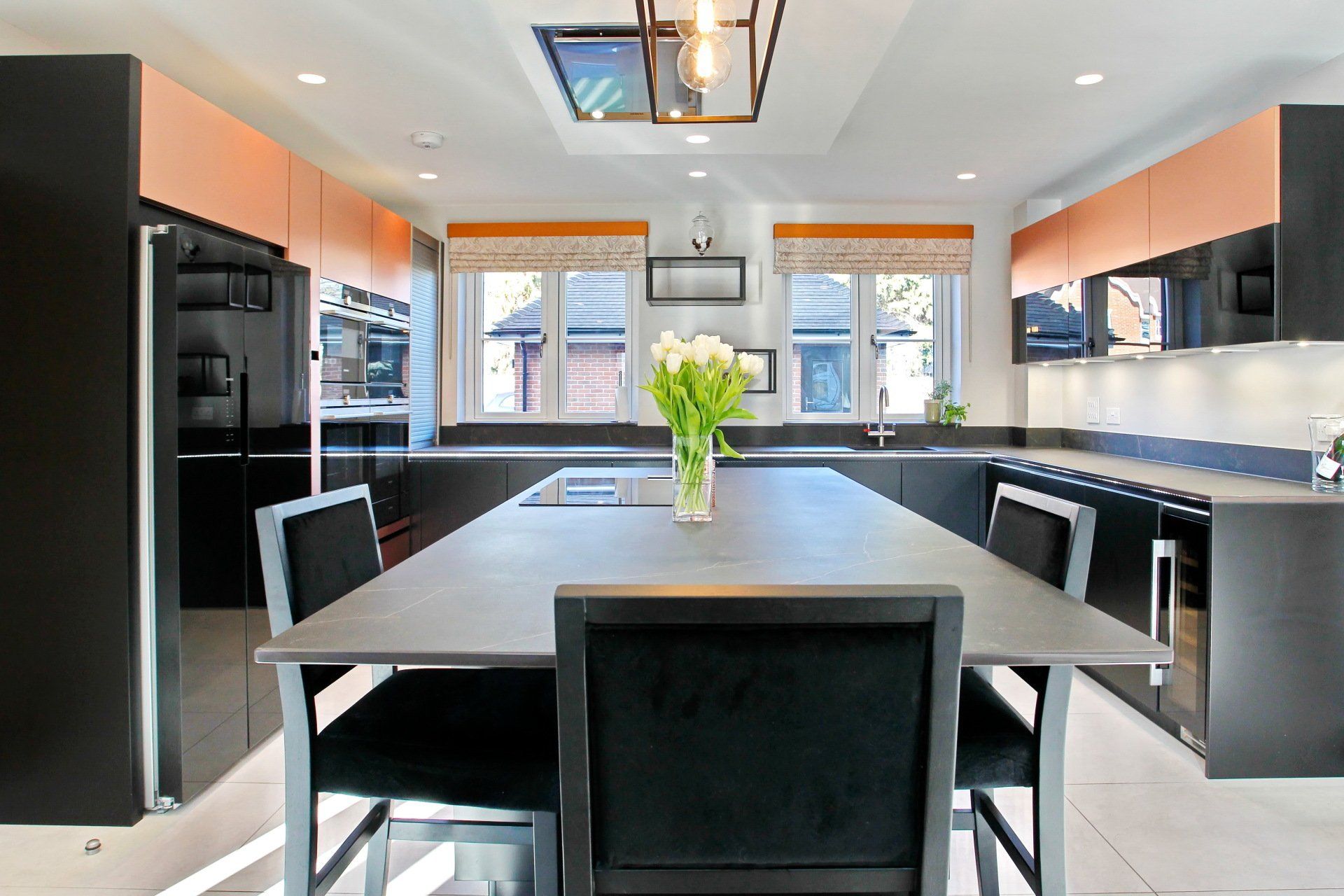 Modern kitchen with black cabinets, copper accents, and a gray dining table.