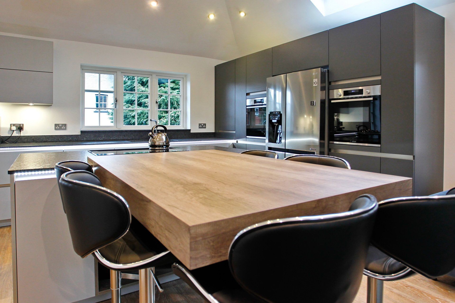 Harvey contemporary kitchen with grey, handleless units and teal furnishings. Designed by exact Kitchens in Wokingham.