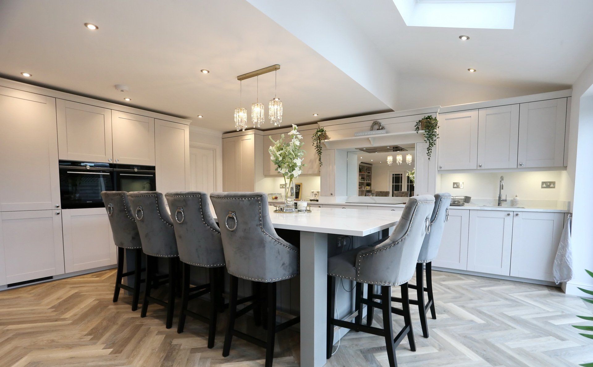 Spacious, light gray kitchen with large island, seating, and overhead lights.