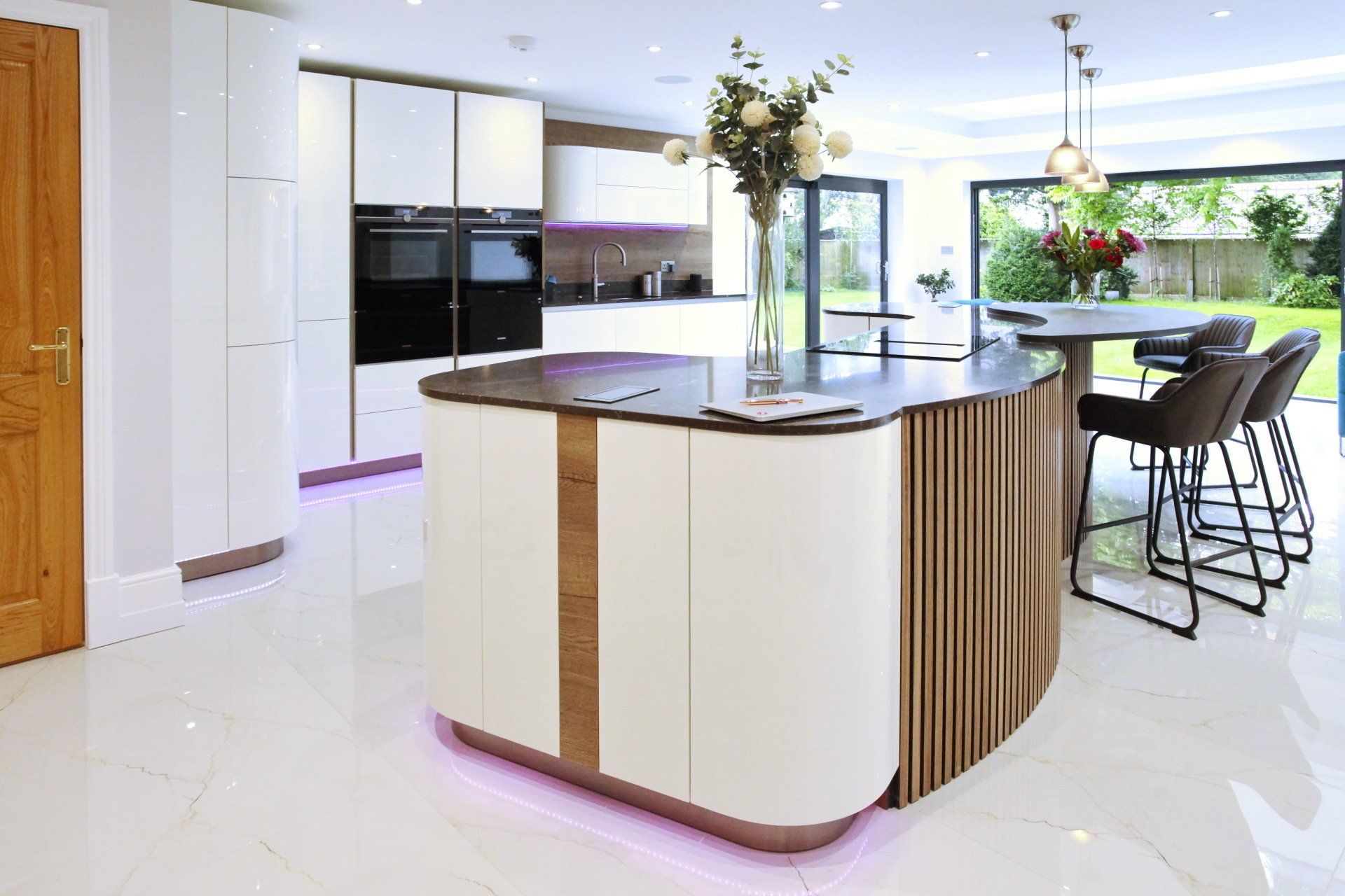 Modern kitchen with white cabinetry, a wood-paneled island, and a dark countertop.