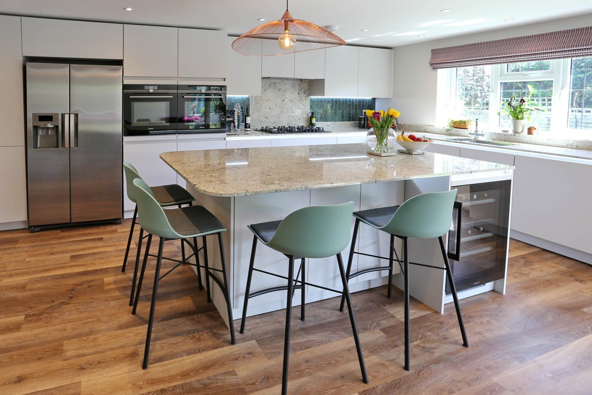 Modern kitchen with white cabinets, island with seating, stainless steel appliances, and wood floor.