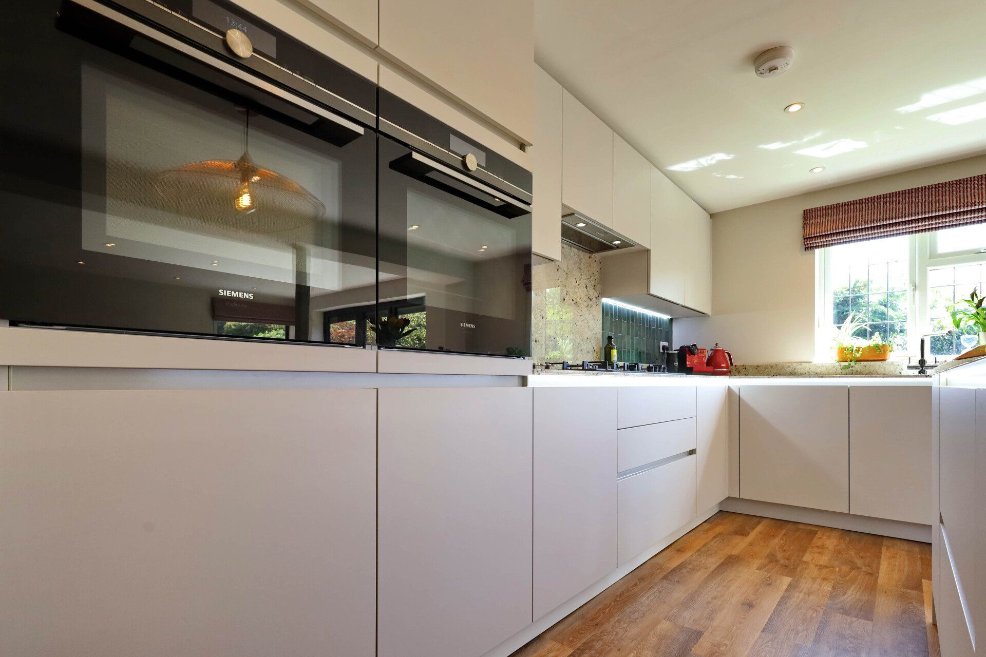 Harvey contemporary kitchen with grey, handleless units and teal furnishings. Designed by exact Kitchens in Wokingham.