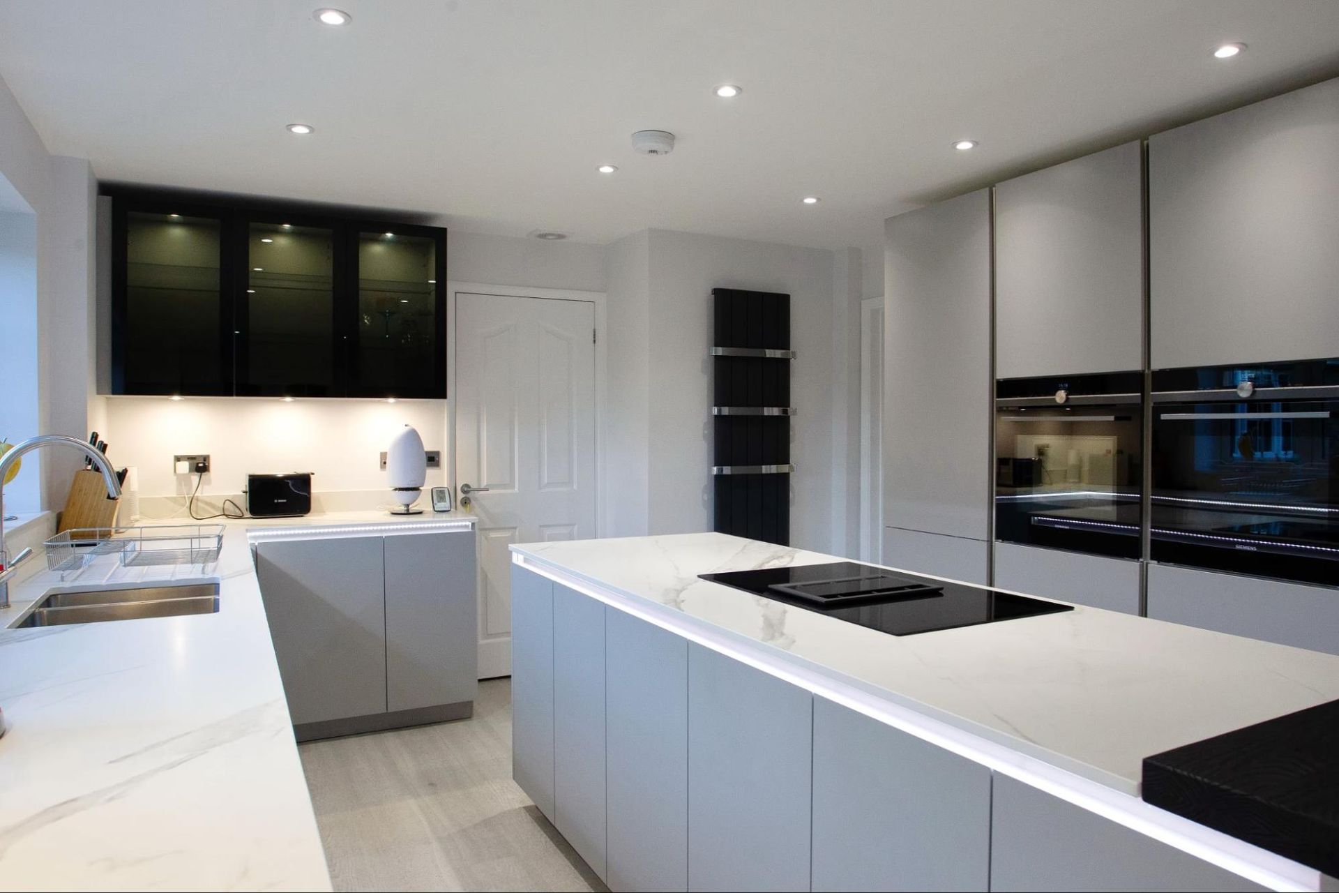 Modern kitchen with grey cabinets, white countertops, and stainless steel appliances.